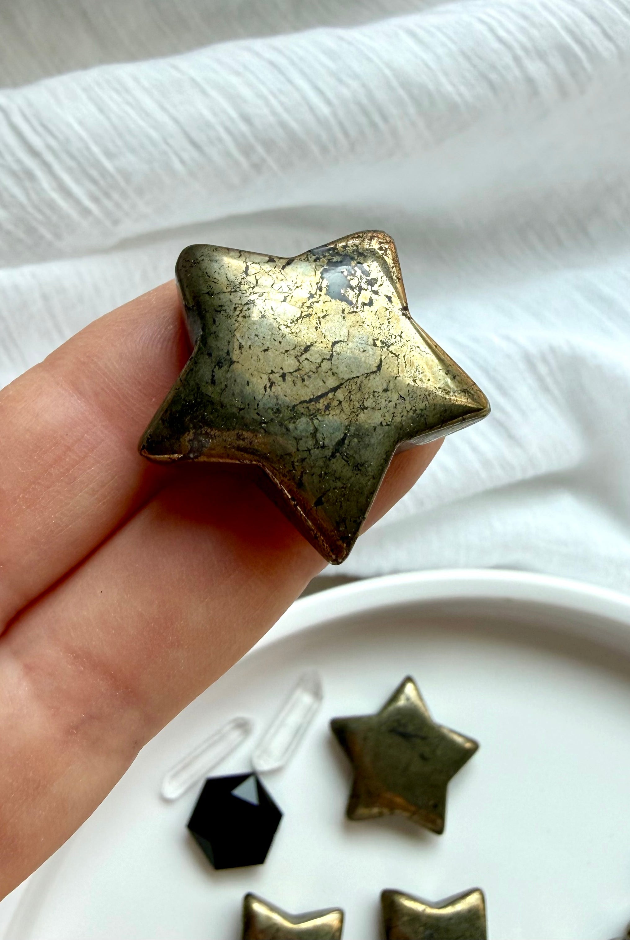 Small Pyrite star carvings displayed in hand for manifestation, prosperity and abundance rituals