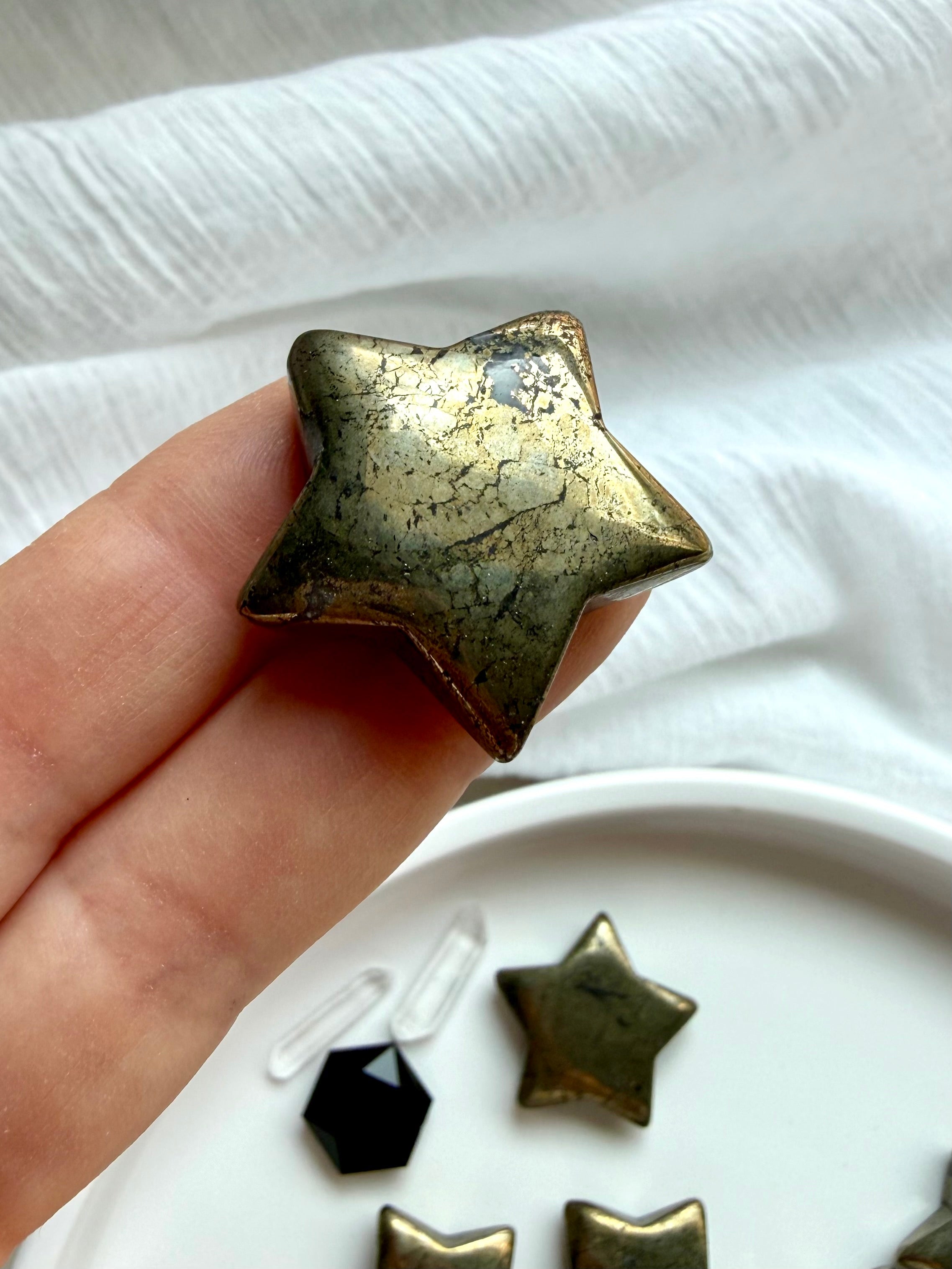 Small Pyrite star carvings displayed in hand for manifestation, prosperity and abundance rituals