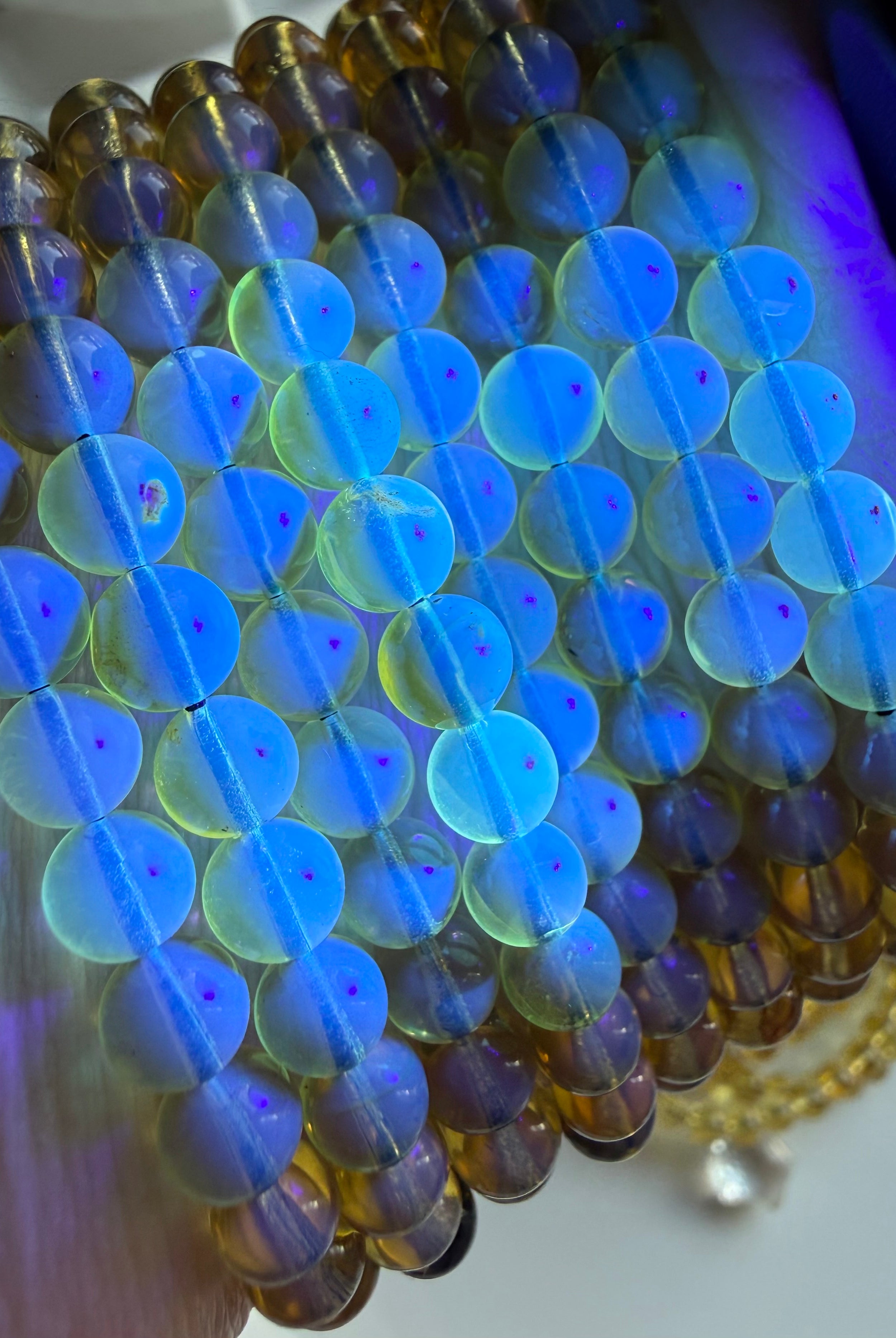 Close-up of Indonesian blue amber bracelet glowing bright blue under UV light showing natural UV reactive amber