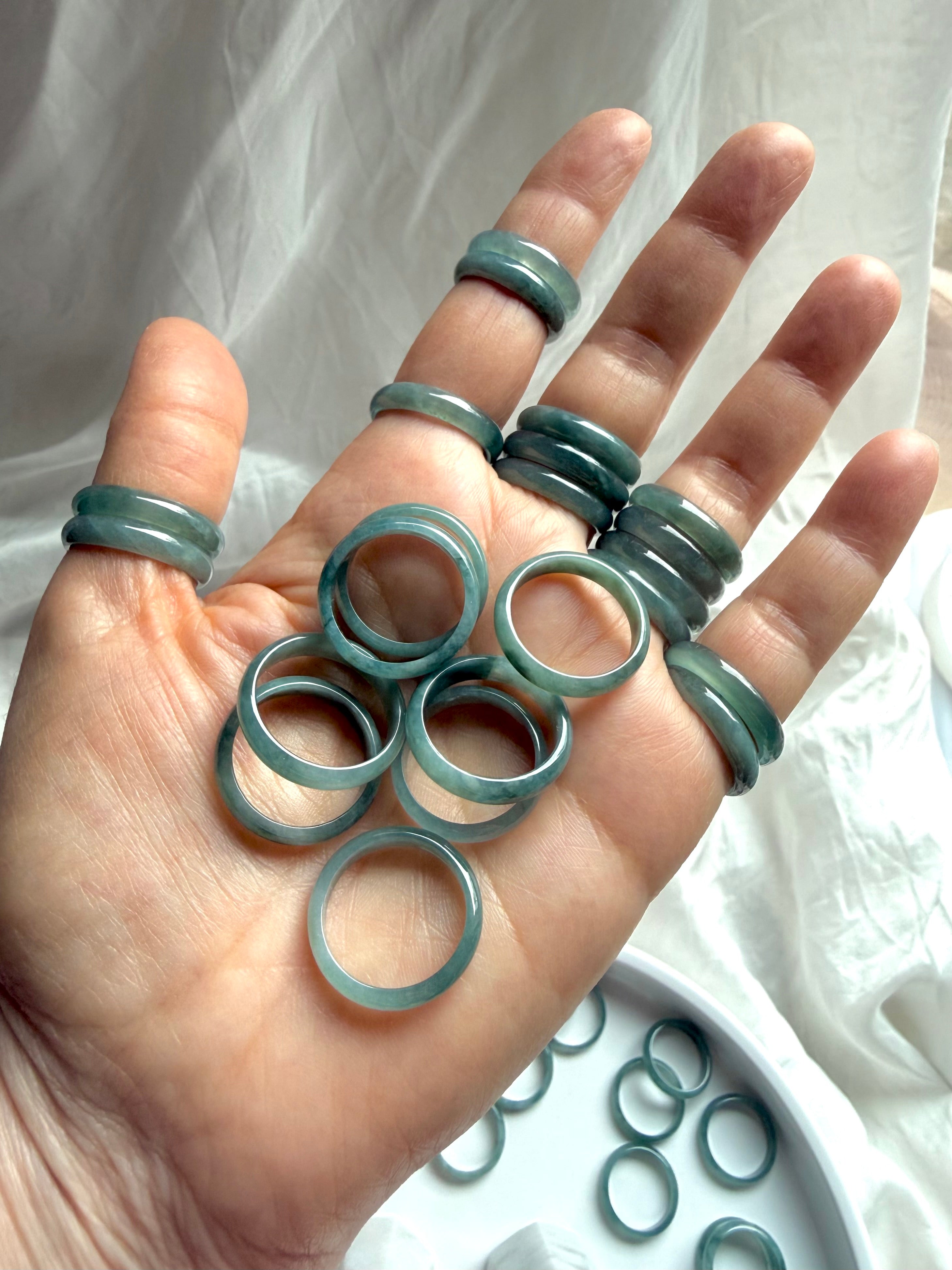 Rounded Blue Water jade rings displayed on open palm, natural jadeite band selection