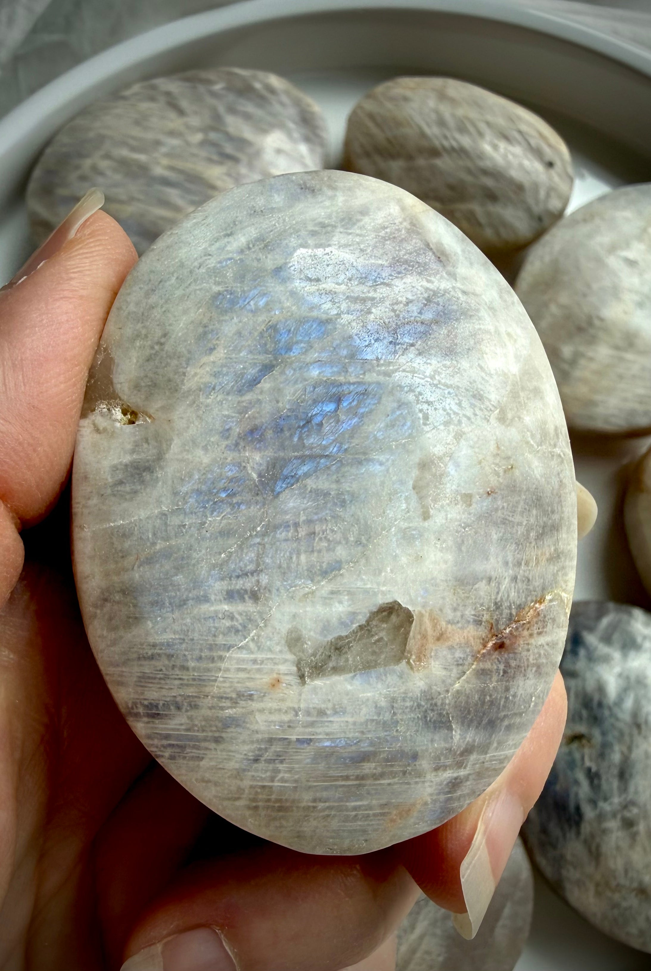 polished belomorite moonstone palm stone with blue flash and silvery gray feldspar patterns