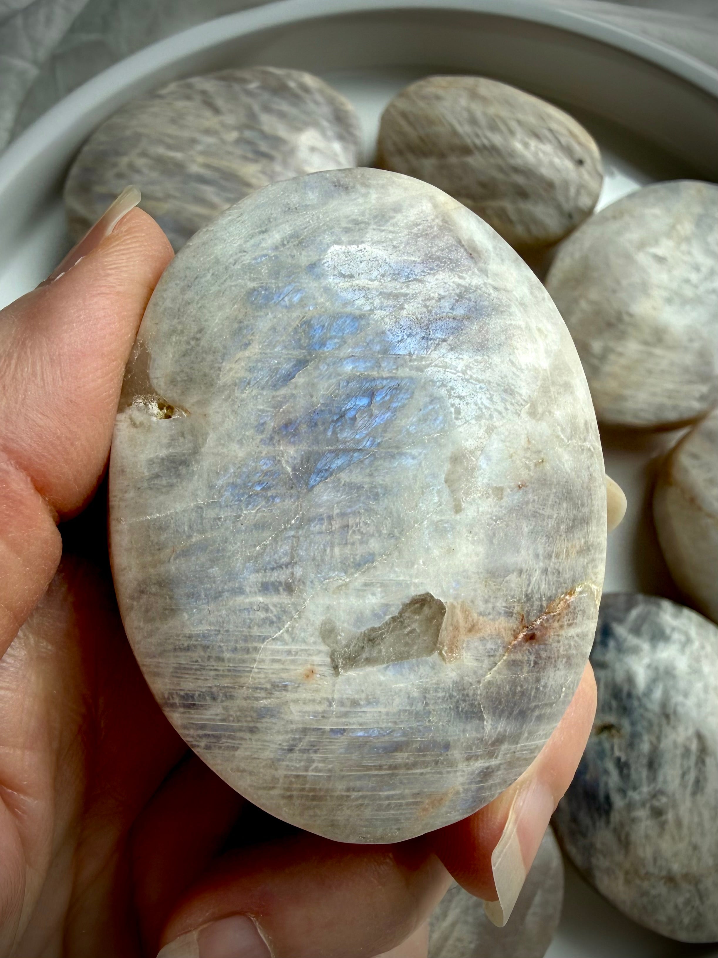 polished belomorite moonstone palm stone with blue flash and silvery gray feldspar patterns