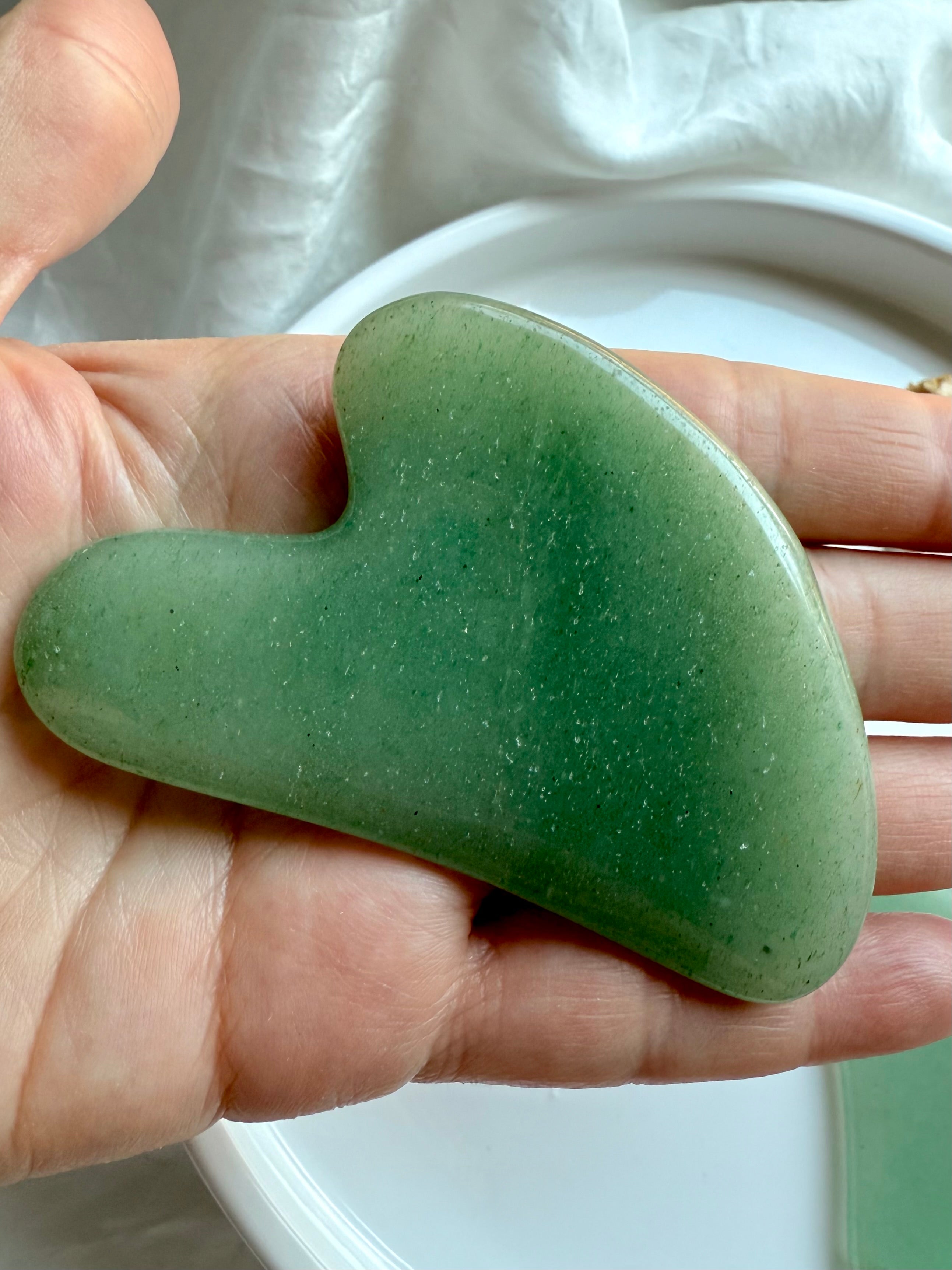 Close-up of Green Aventurine crystal gua sha facial massage tool resting in hand