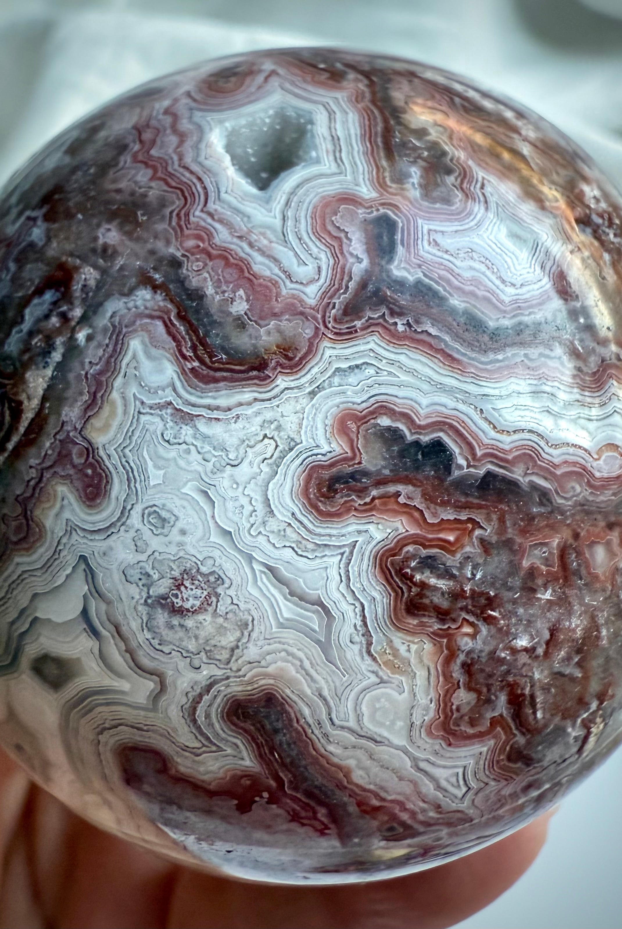 Red and white Crazy Lace Agate sphere with layered patterning and joyful root chakra vibrations
