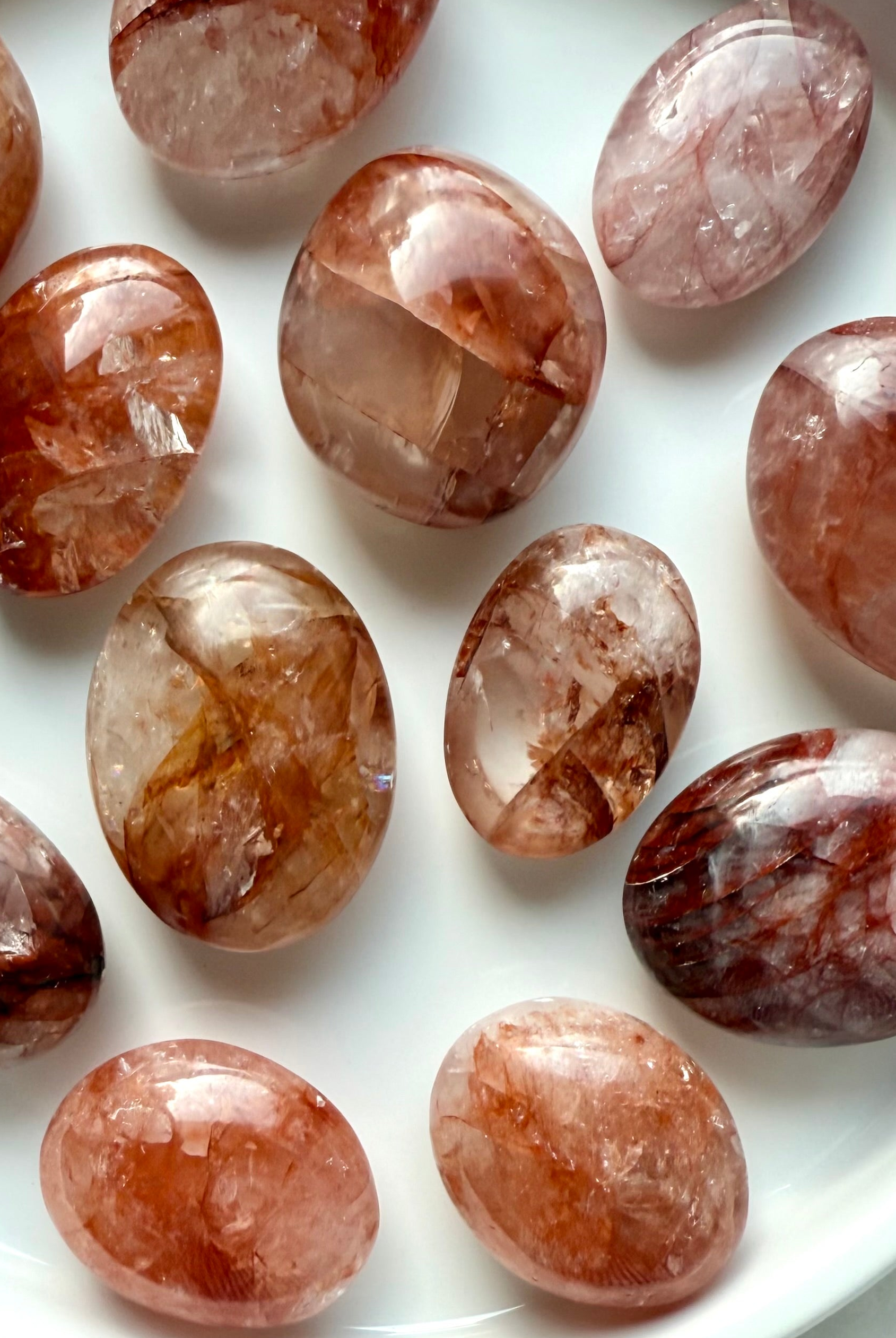Closeup of polished Fire Quartz palm stones in a white dish for root chakra energy healing