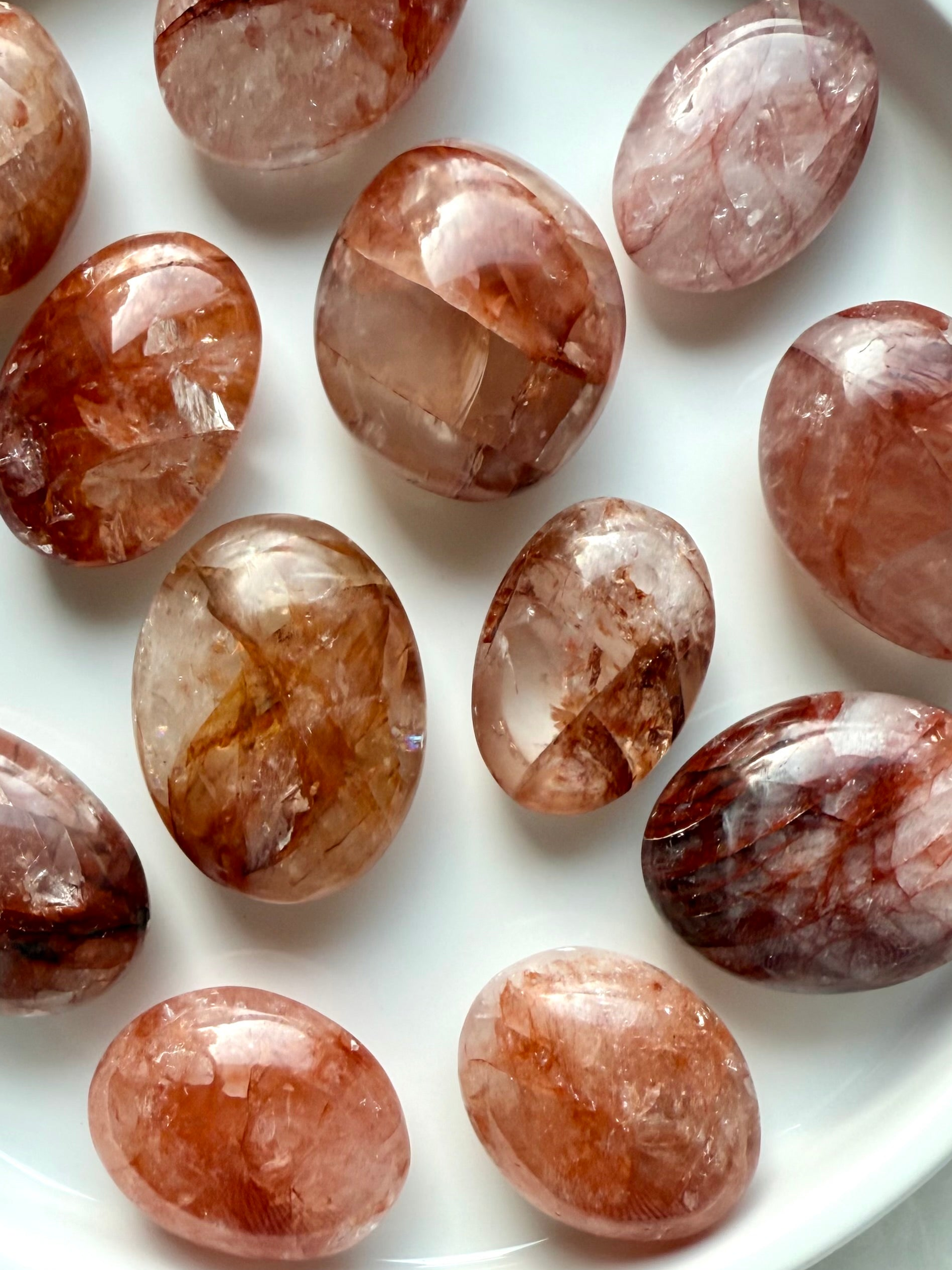 Closeup of polished Fire Quartz palm stones in a white dish for root chakra energy healing