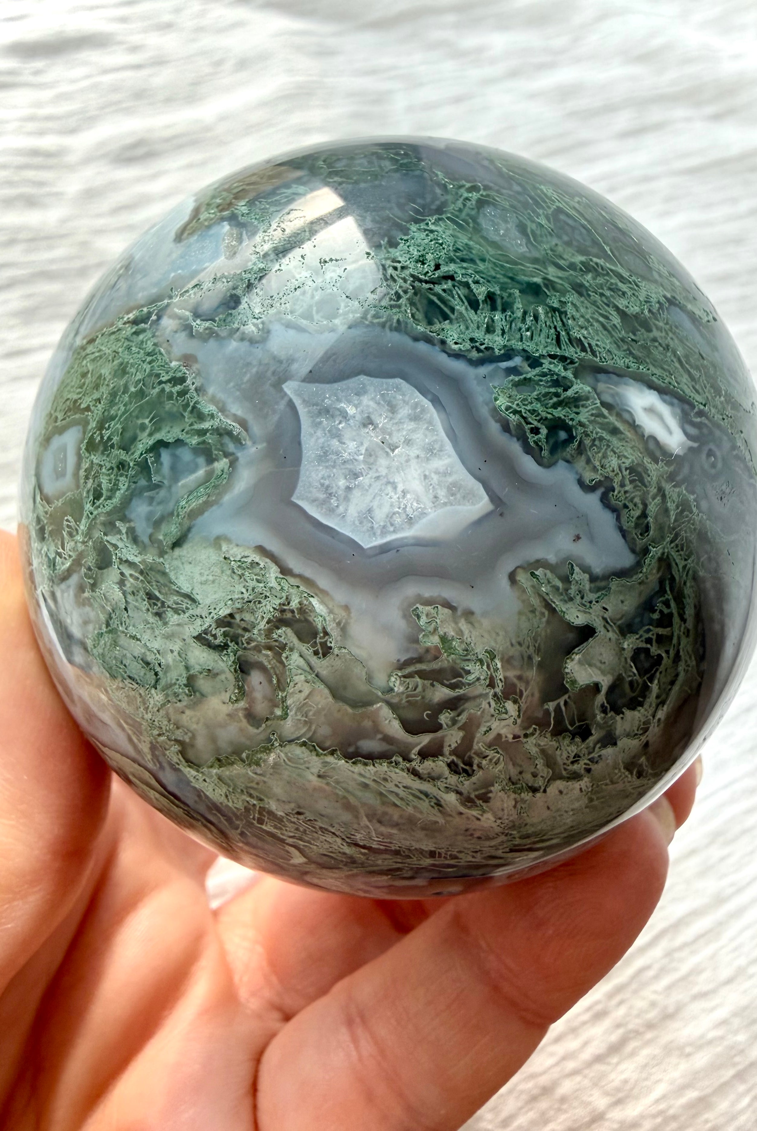 Polished Moss Agate sphere with intricate botanical dendrites and layered gray chalcedony