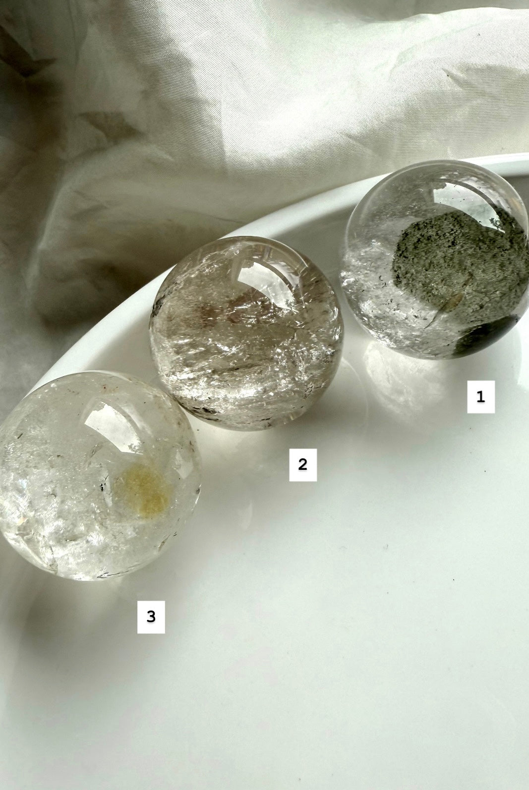 three lodolite quartz spheres on a white plate – garden quartz spheres for spiritual healing