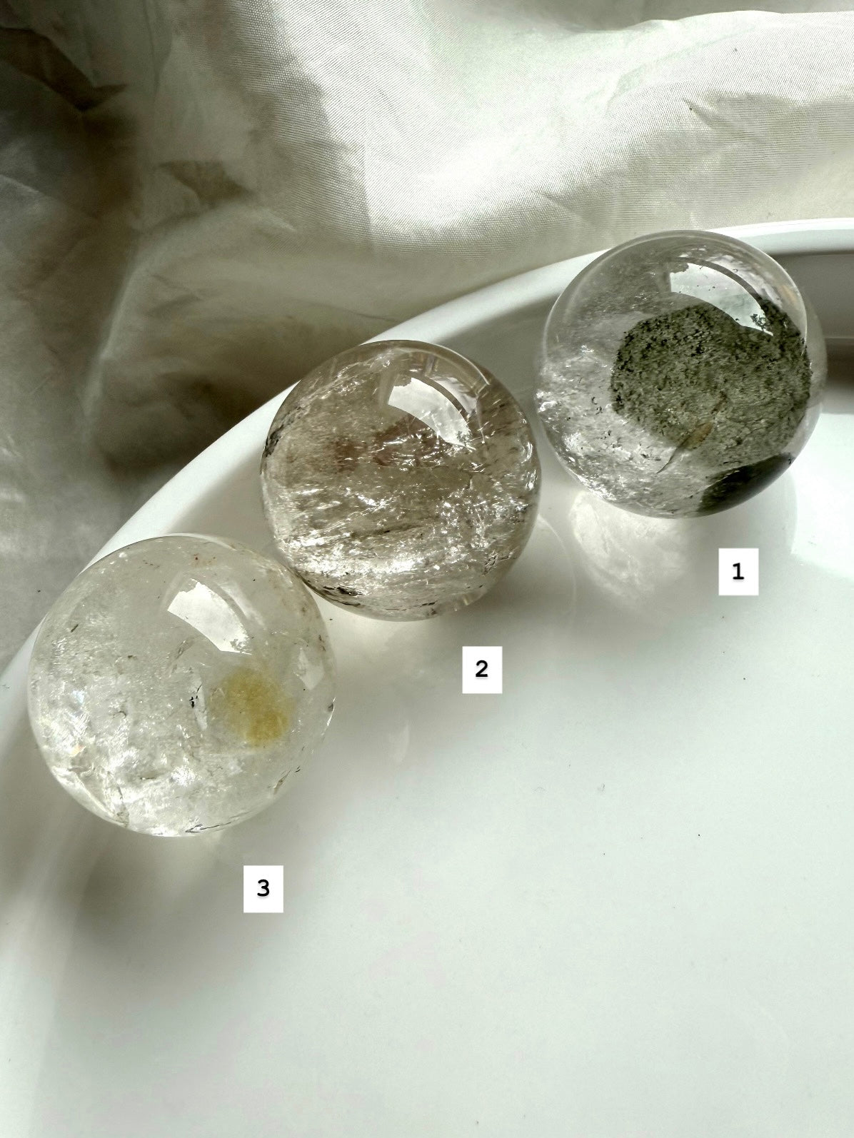 three lodolite quartz spheres on a white plate – garden quartz spheres for spiritual healing
