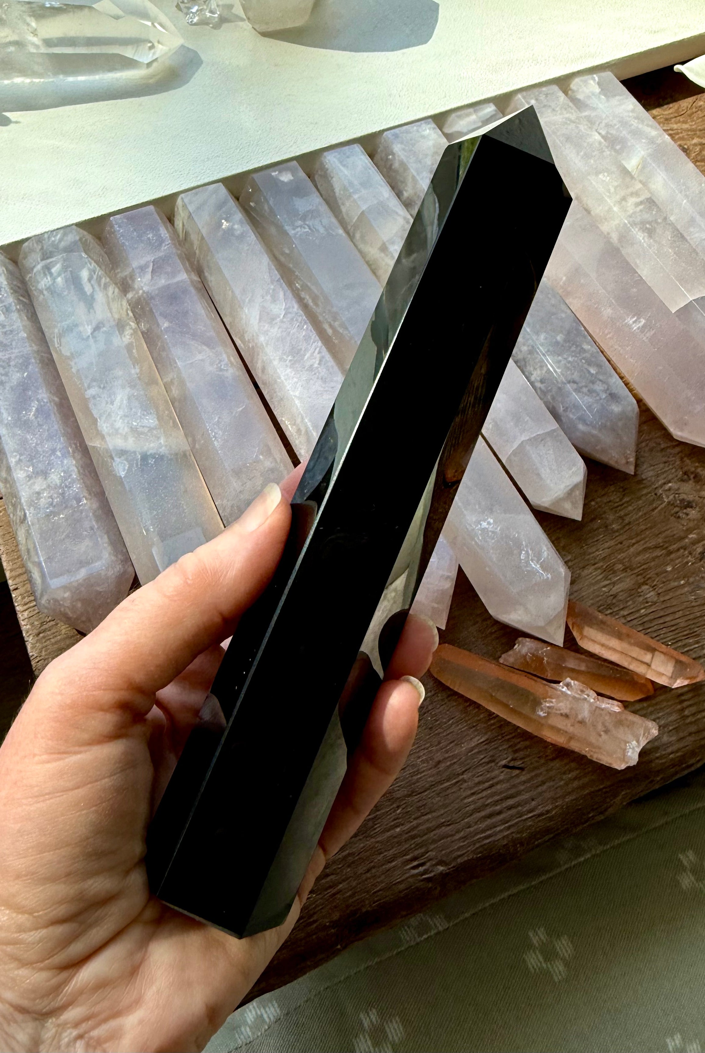 Large Black Obsidian tower angled over a row of rose quartz points — grounding stone for crystal grids & altar décor.