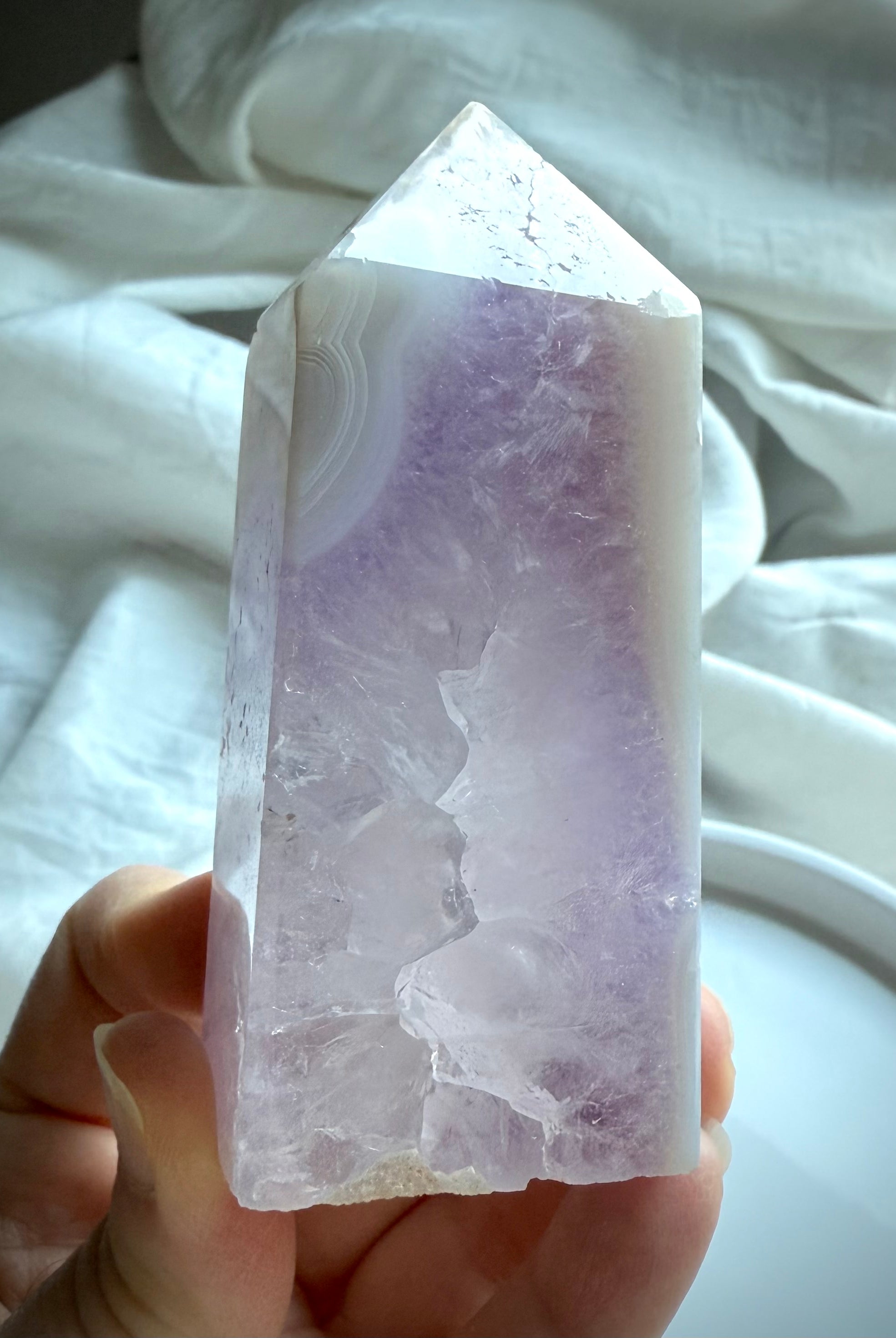 Hand holding Amethyst Geode Tower with lavender core and banded agate tip