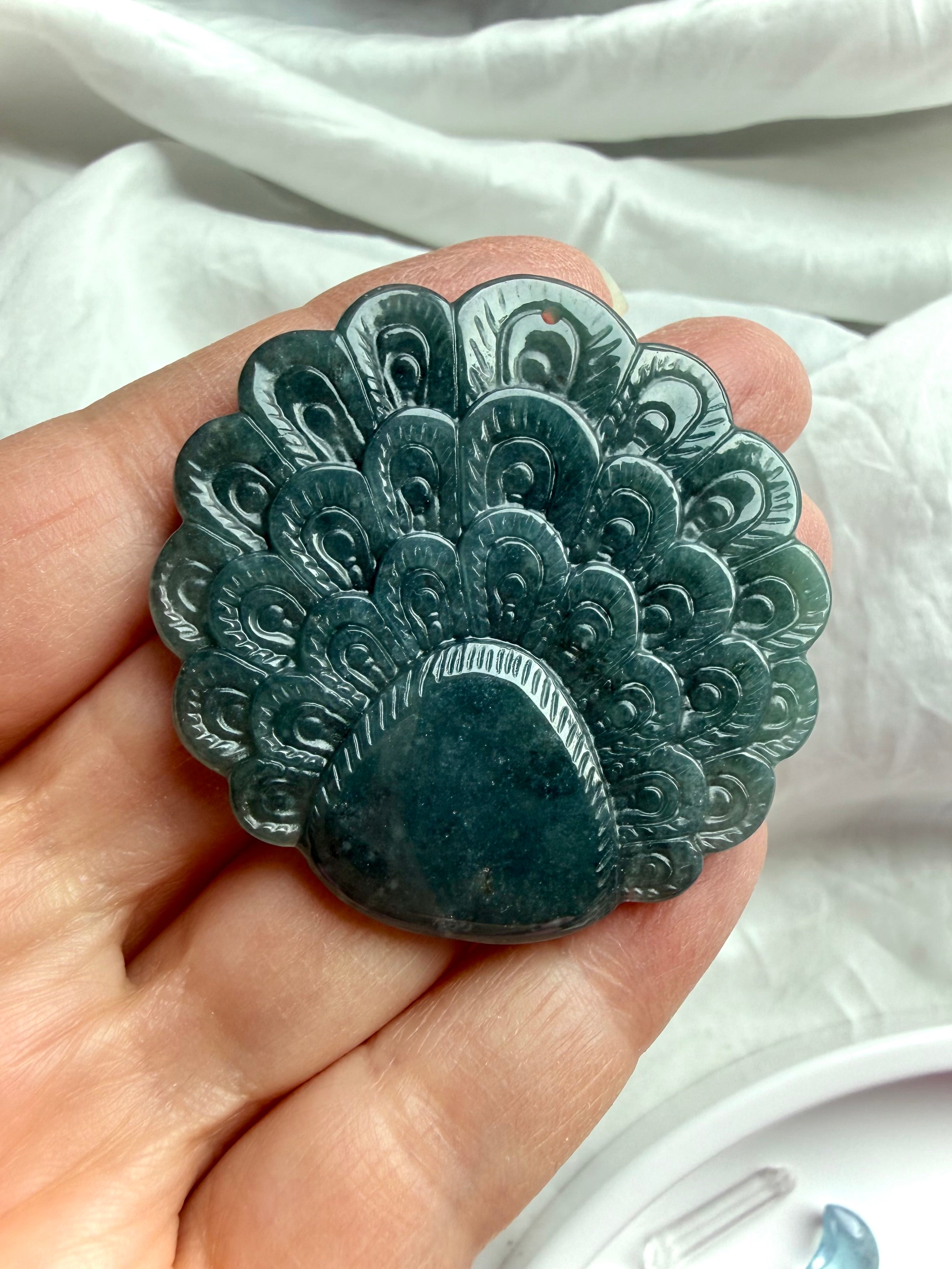 Back view of a Blue Water Jade peacock carving with detailed feather pattern and polished finish