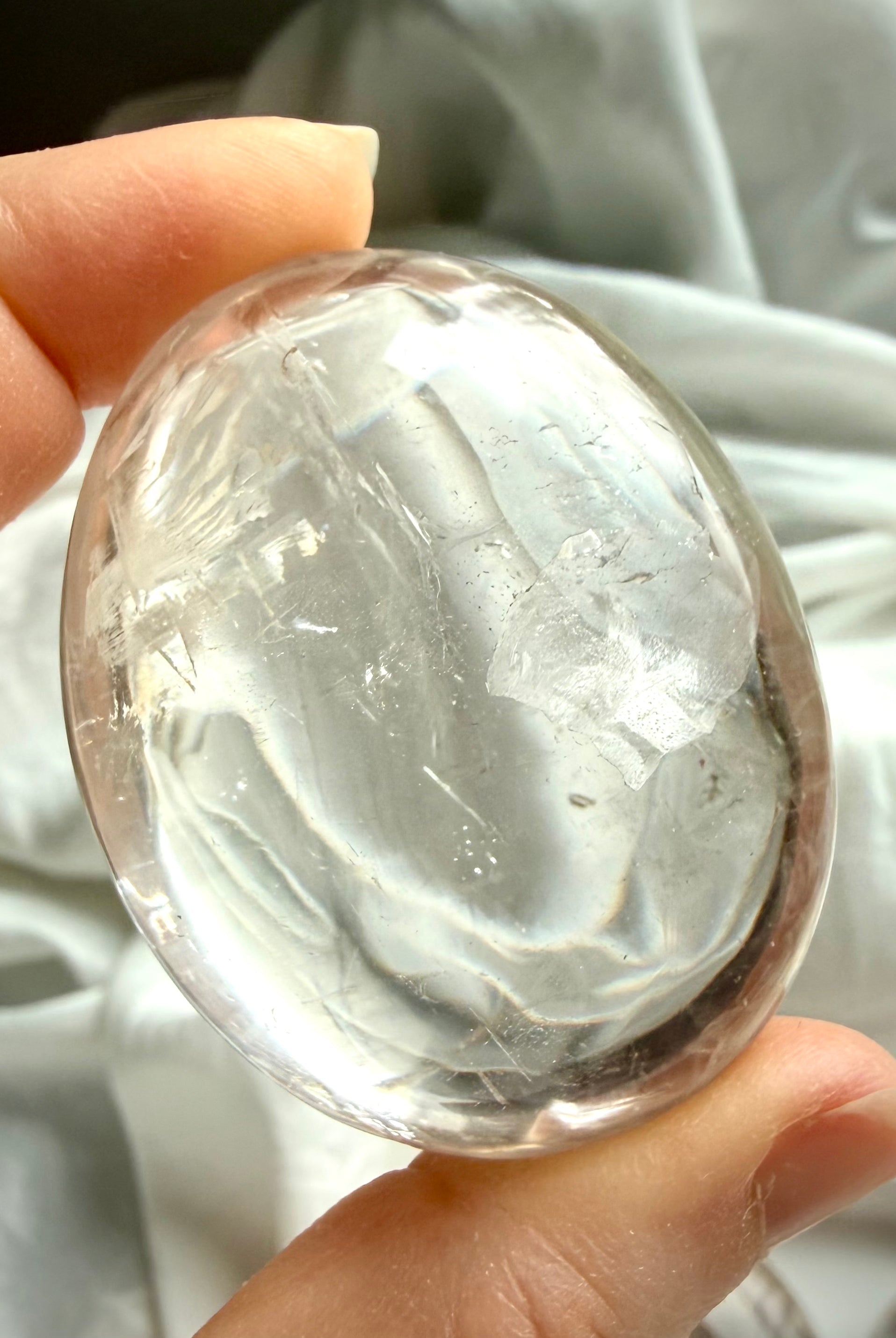 Detailed image of a clear quartz palm stone with subtle inclusions and internal structure