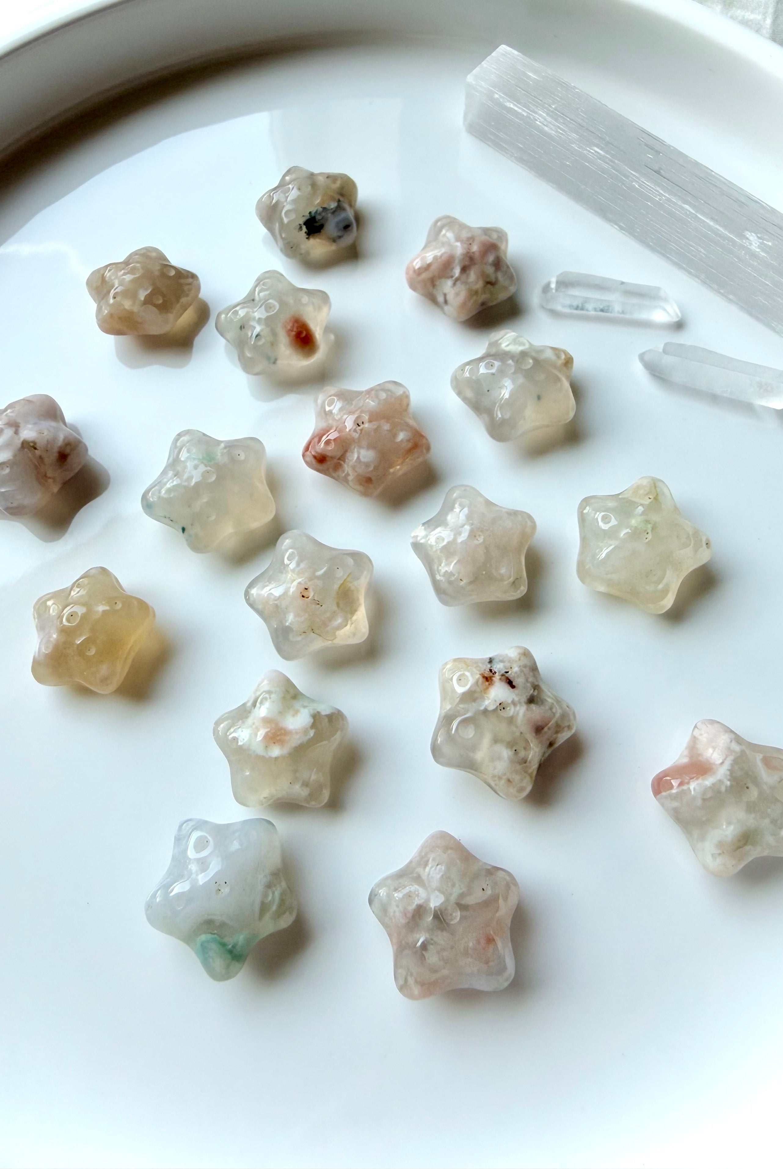 assorted mini Flower Agate starfish carvings arranged on plate with natural floral inclusions and ocean-inspired shape