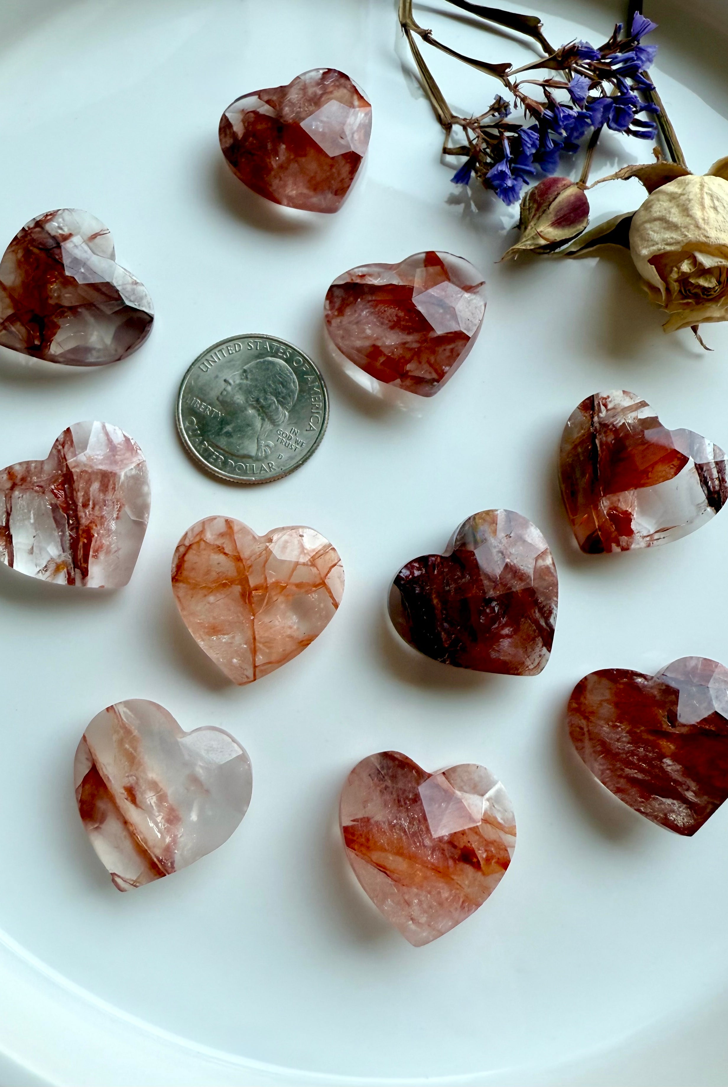 Faceted Fire Quartz hearts in white bowl with quarter for size reference – hand-carved grounding crystals for Root Chakra energy healing