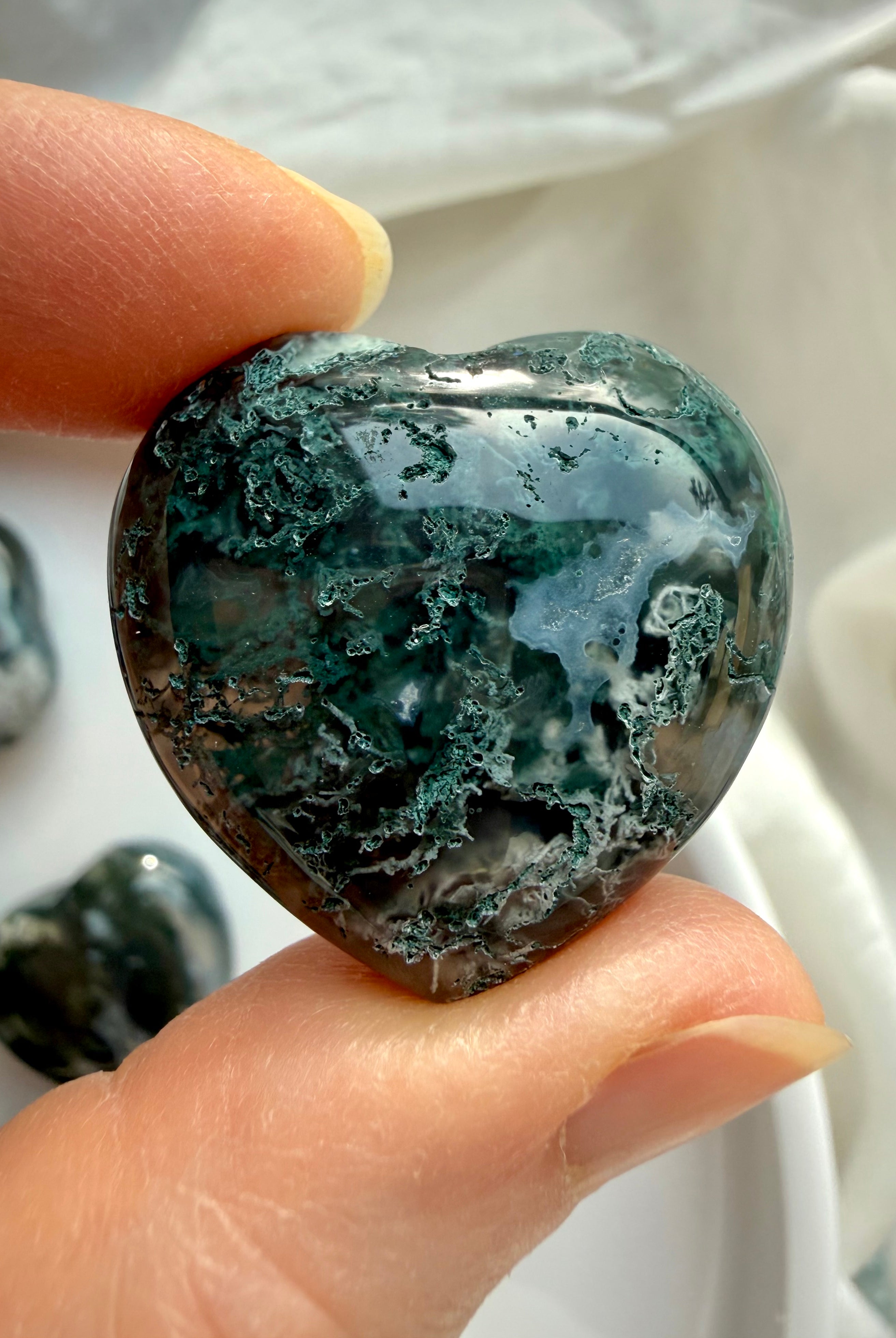 Close-up of a Moss Agate heart showing rich forest-green moss inclusions and organic stone texture