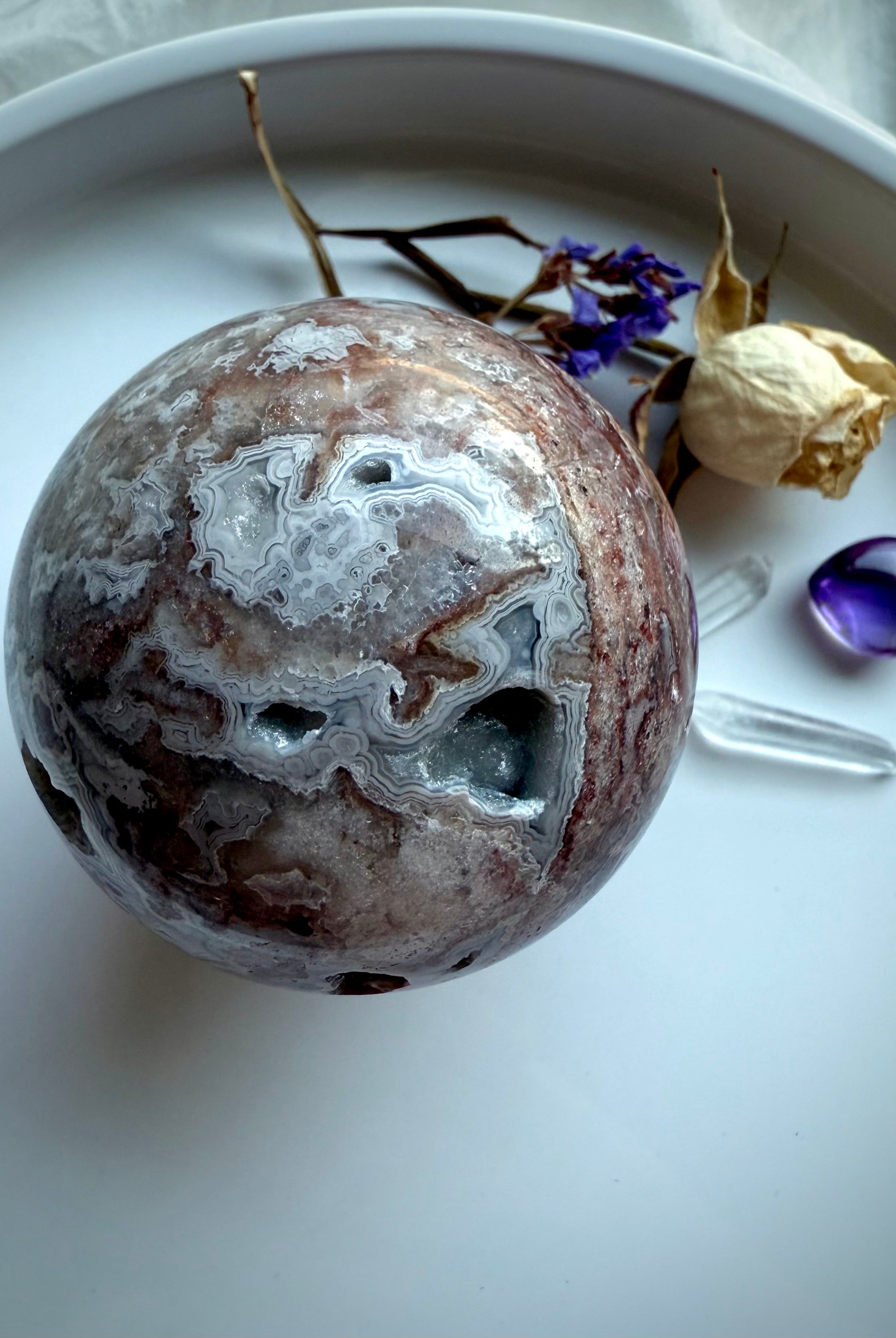 Crystal sphere of Crazy Lace Agate viewed from above with striking red bands and grounding metaphysical properties