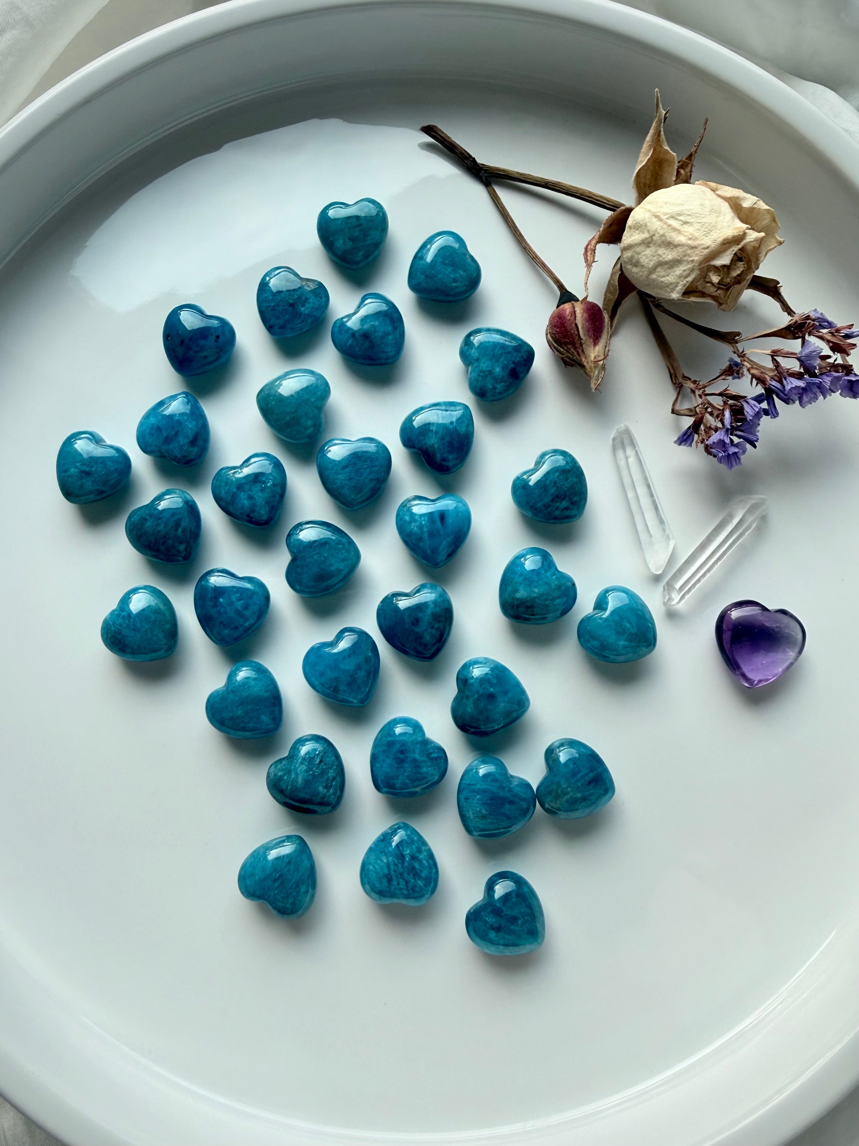 Flatlay of assorted mini Blue Apatite heart carvings, each uniquely patterned with natural blue hues and polished finish