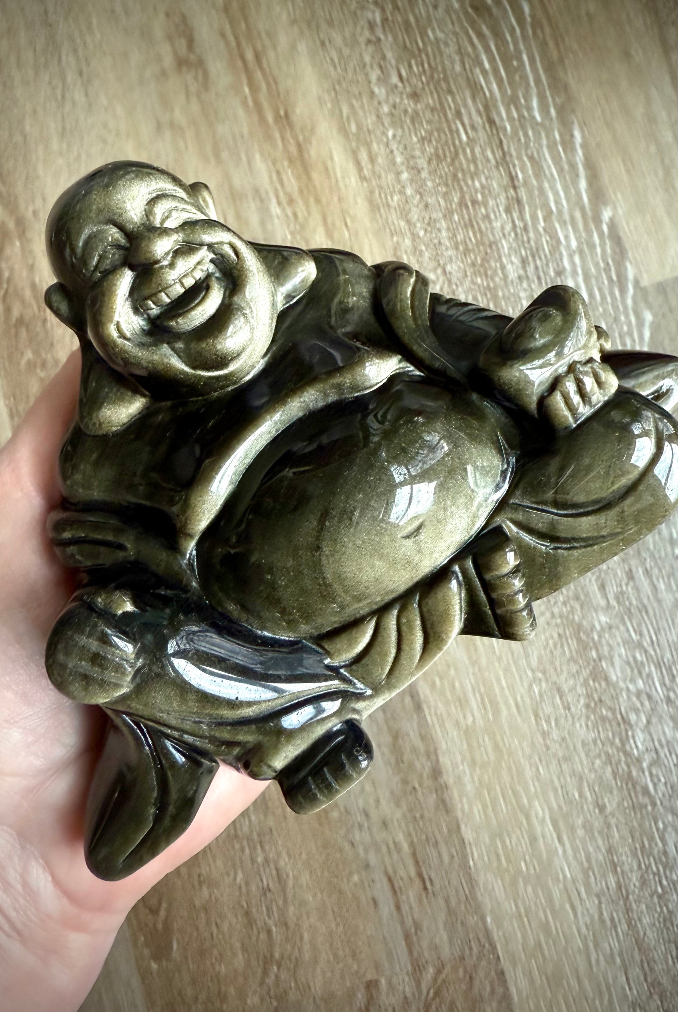 Golden Sheen Obsidian Laughing Buddha statue shown in hand – hand-carved crystal carving for joy, empowerment, and transformation