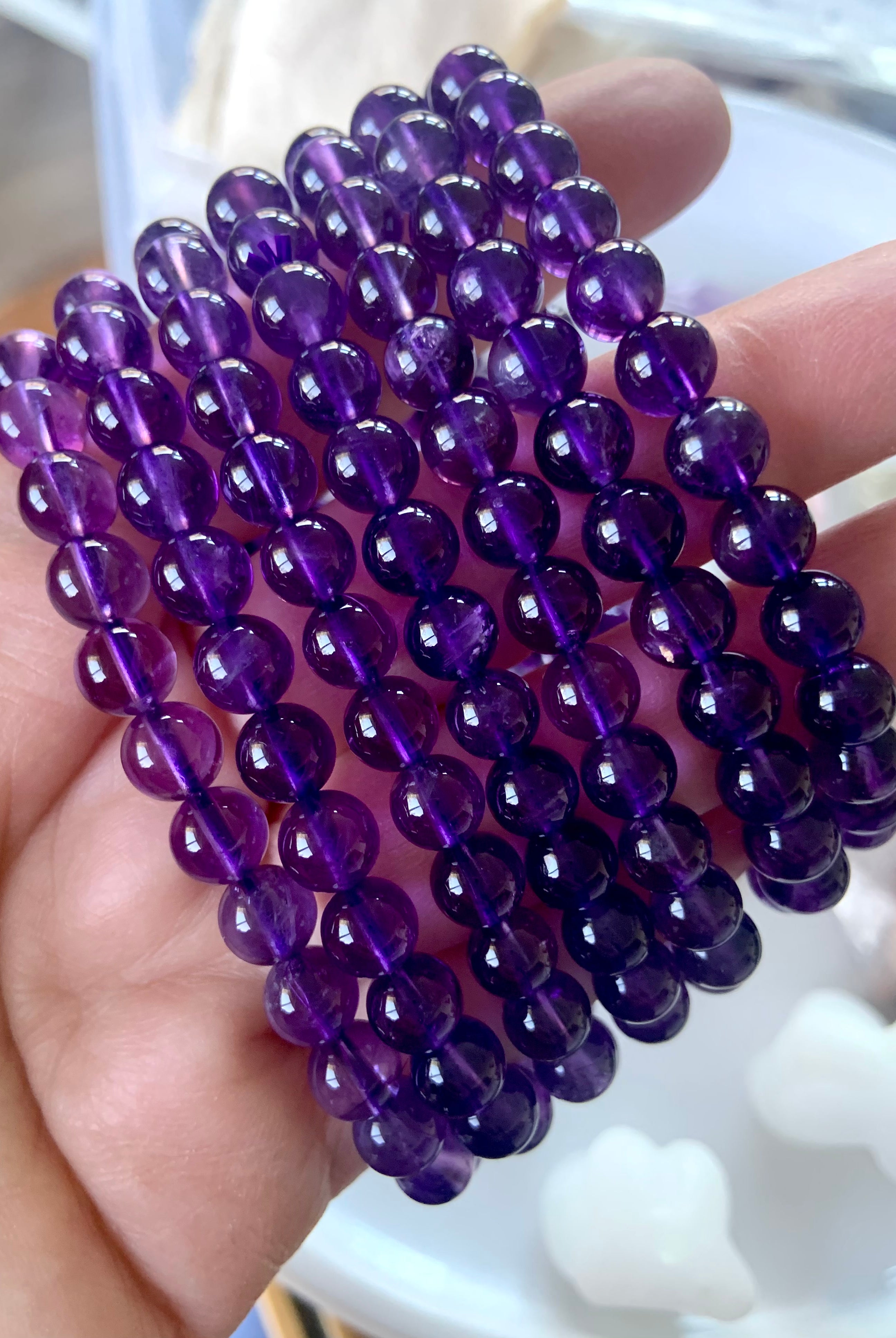 An array of high quality deep purple amethyst beaded bracelets shown on a hand