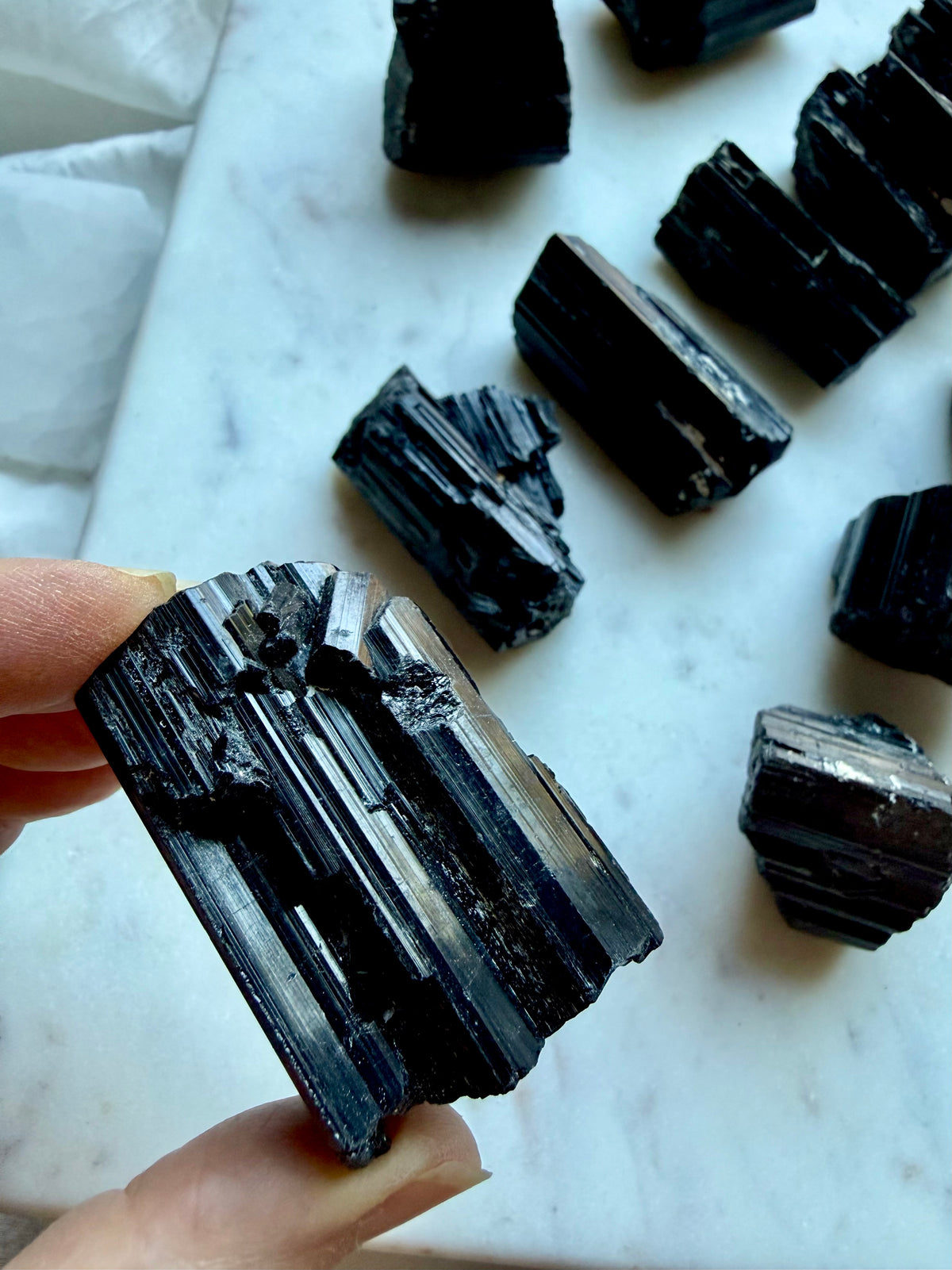 Natural Black Tourmaline chunks showing rough unpolished surfaces, glossy striations, and varied crystal growth