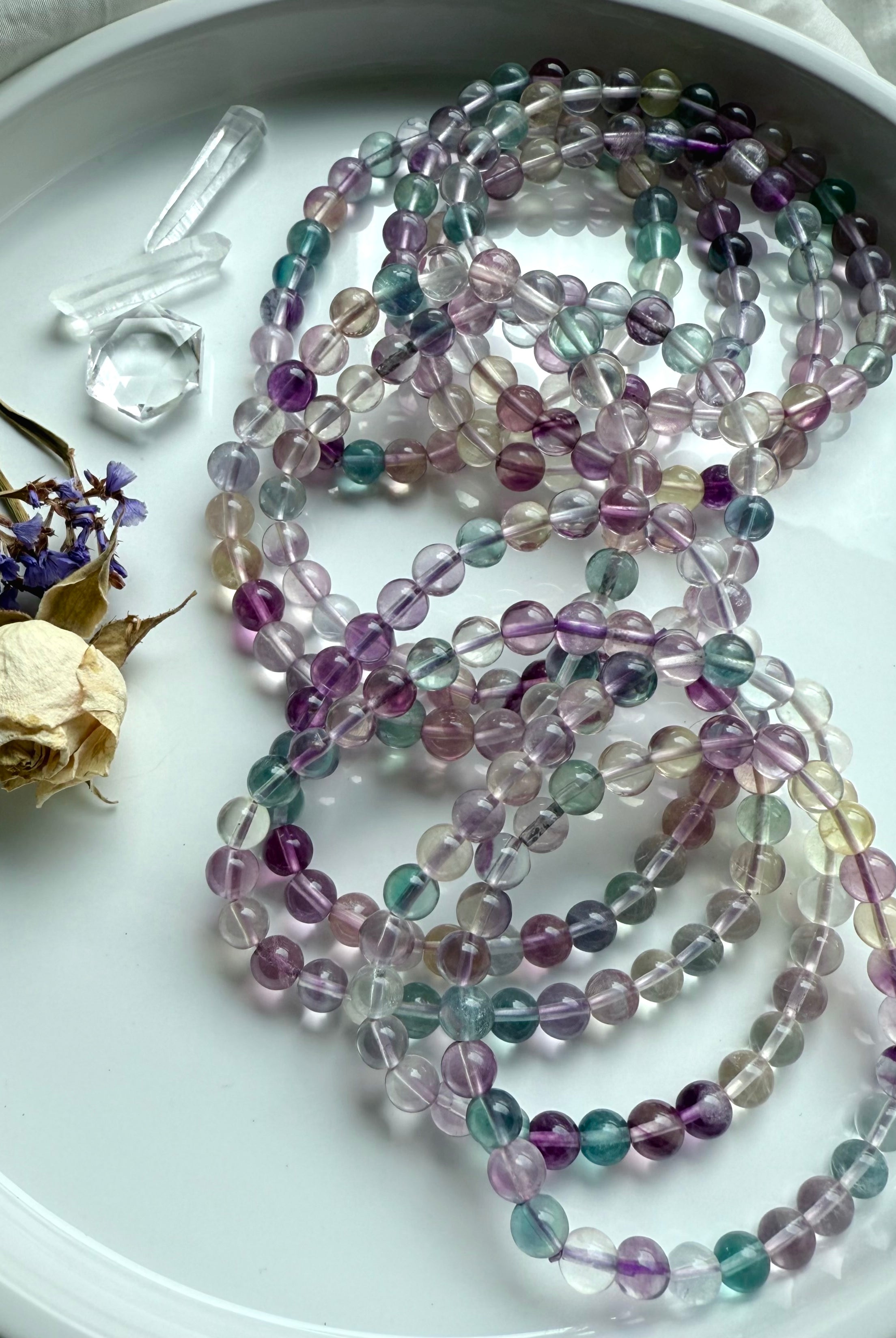 Rainbow fluorite bracelet styled with clear quartz points and dried flowers for a calming crystal aesthetic