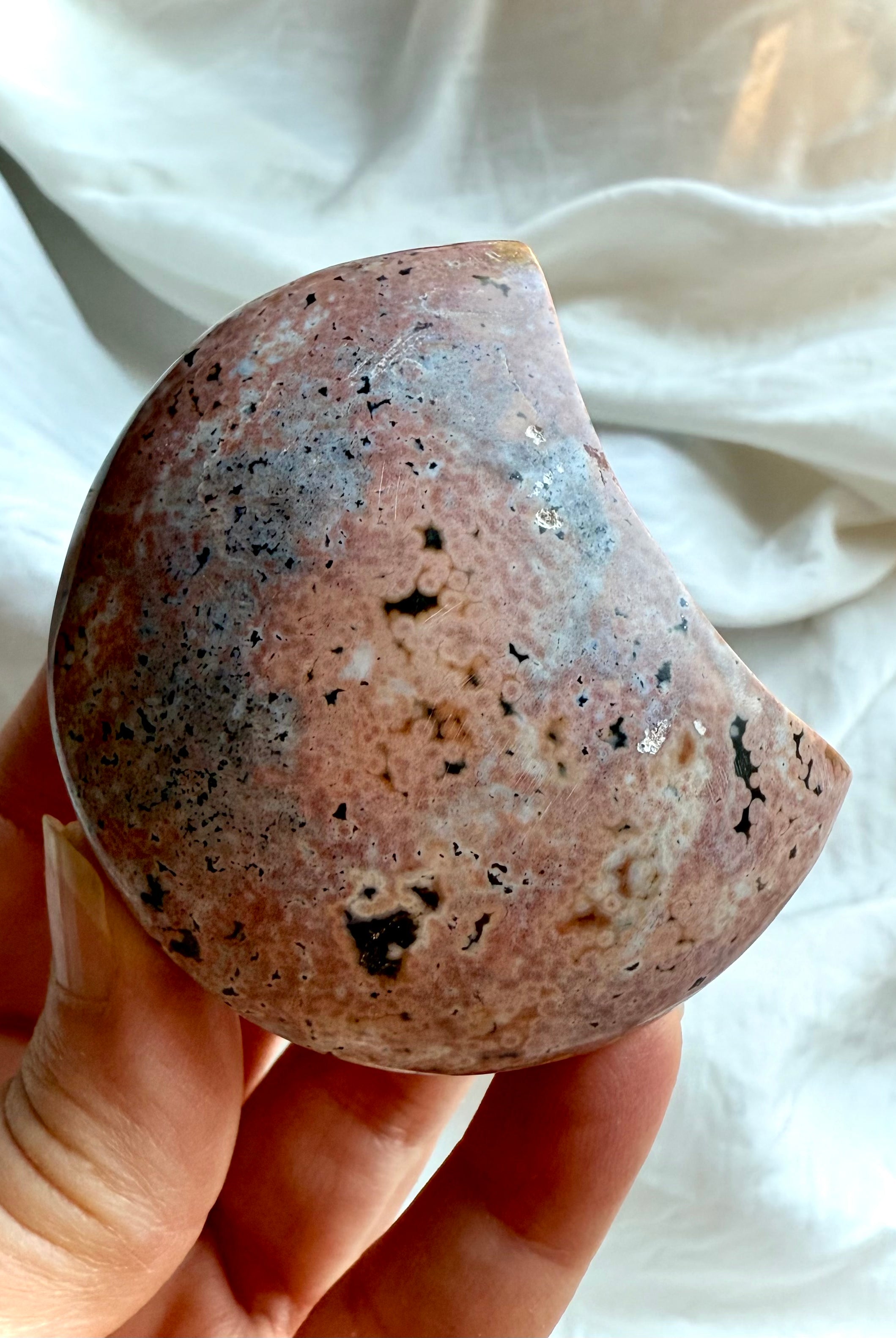 back view of ocean jasper moon showing soft pink, peach, and grey orbicular patterns, natural gemstone carving for grounding and emotional harmony