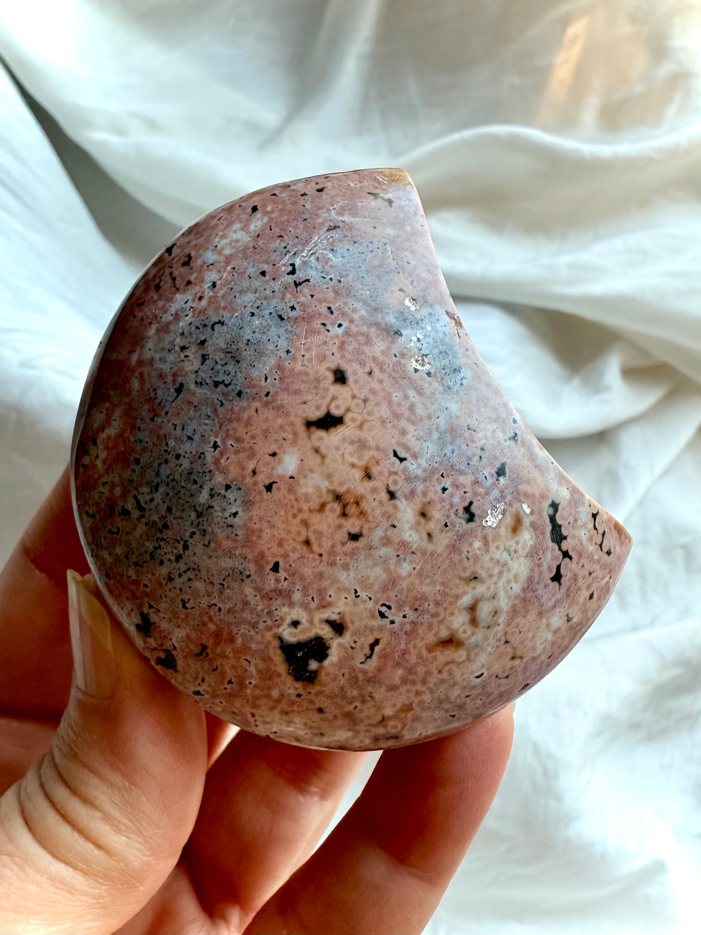 back view of ocean jasper moon showing soft pink, peach, and grey orbicular patterns, natural gemstone carving for grounding and emotional harmony