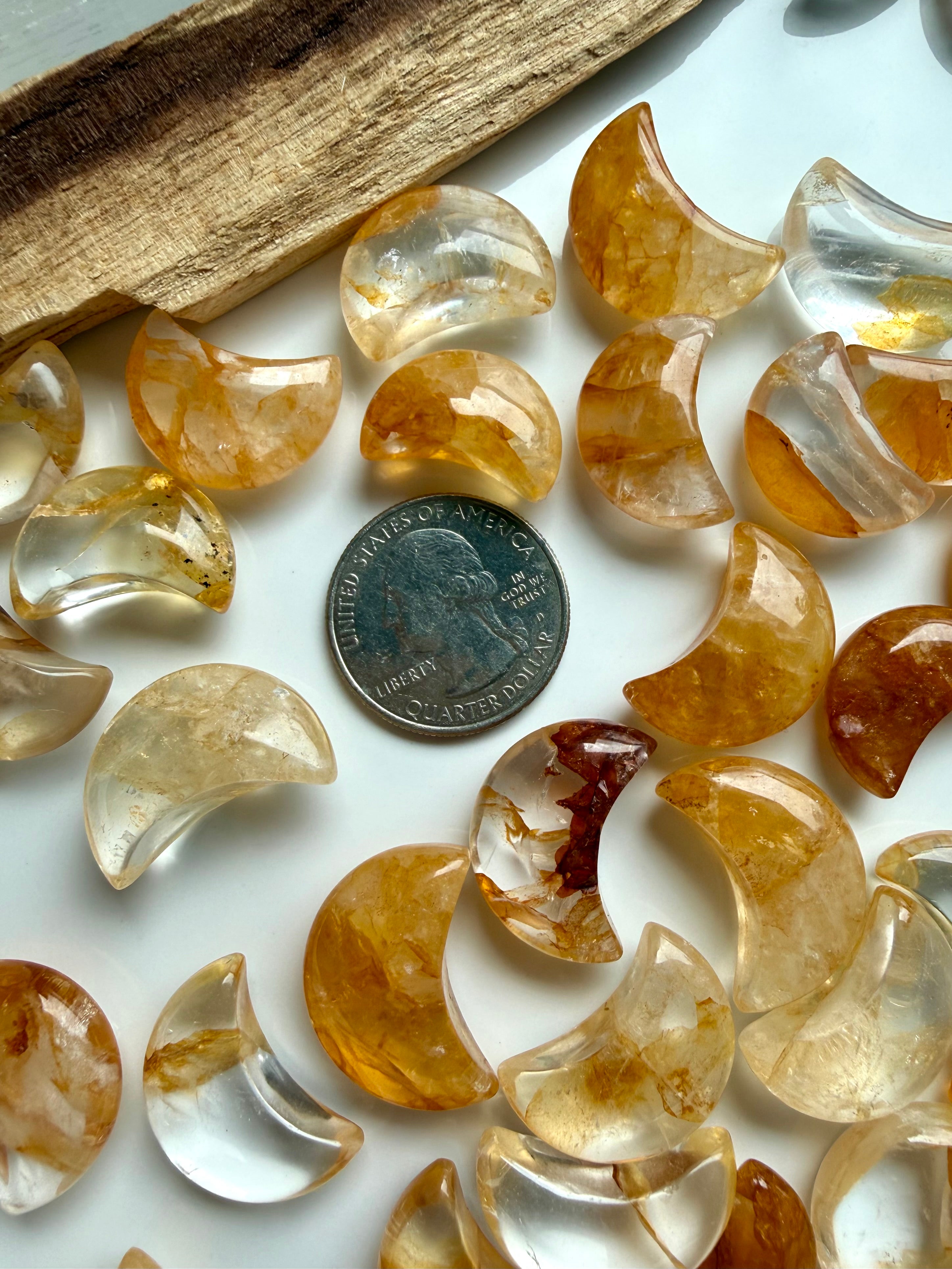 Golden Healer crystal moons in assorted sizes with natural patterns, clarity, and unique golden coloring shown with a US quarter for scale