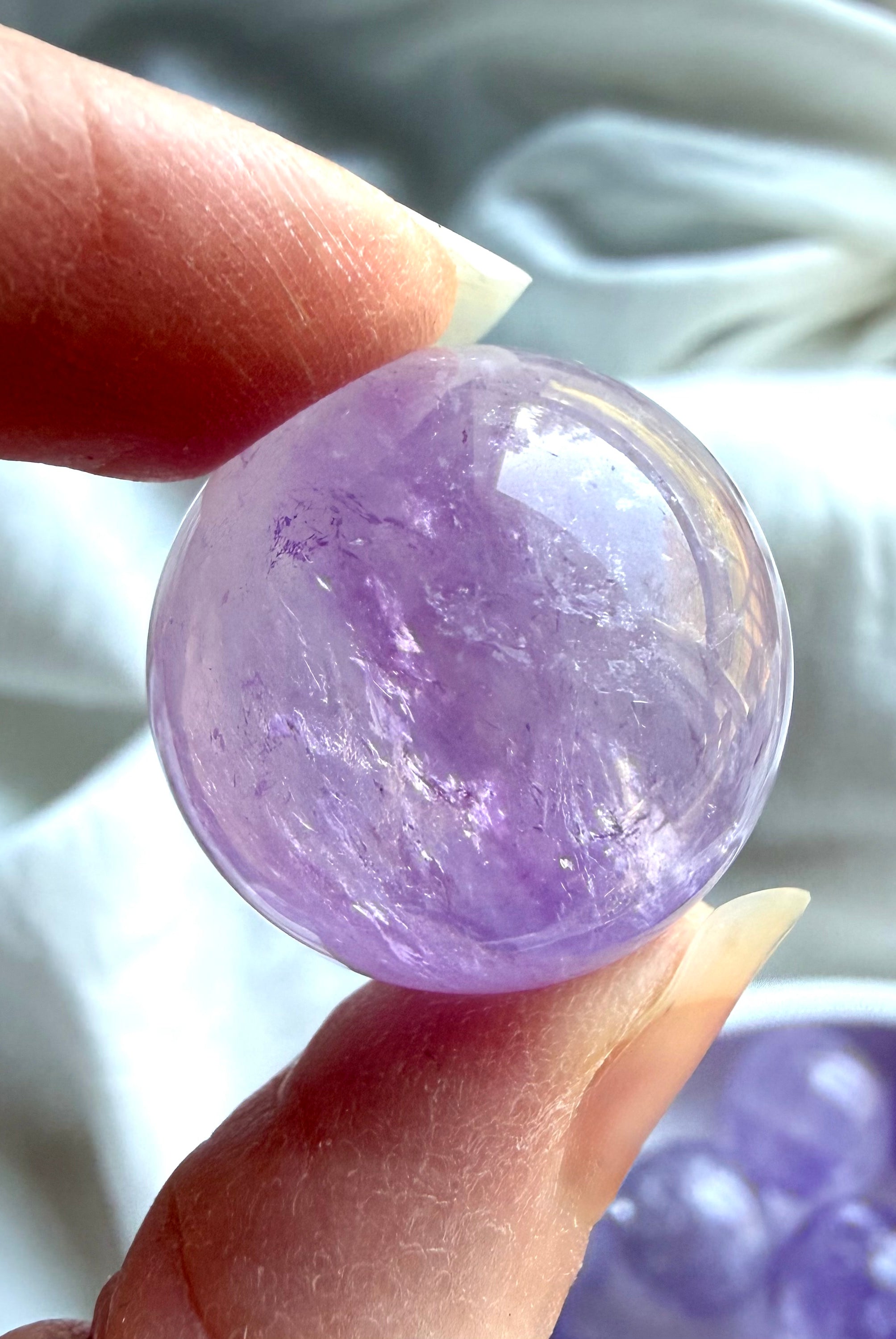 small smoky amethyst crystal sphere held in hand showing size and clarity