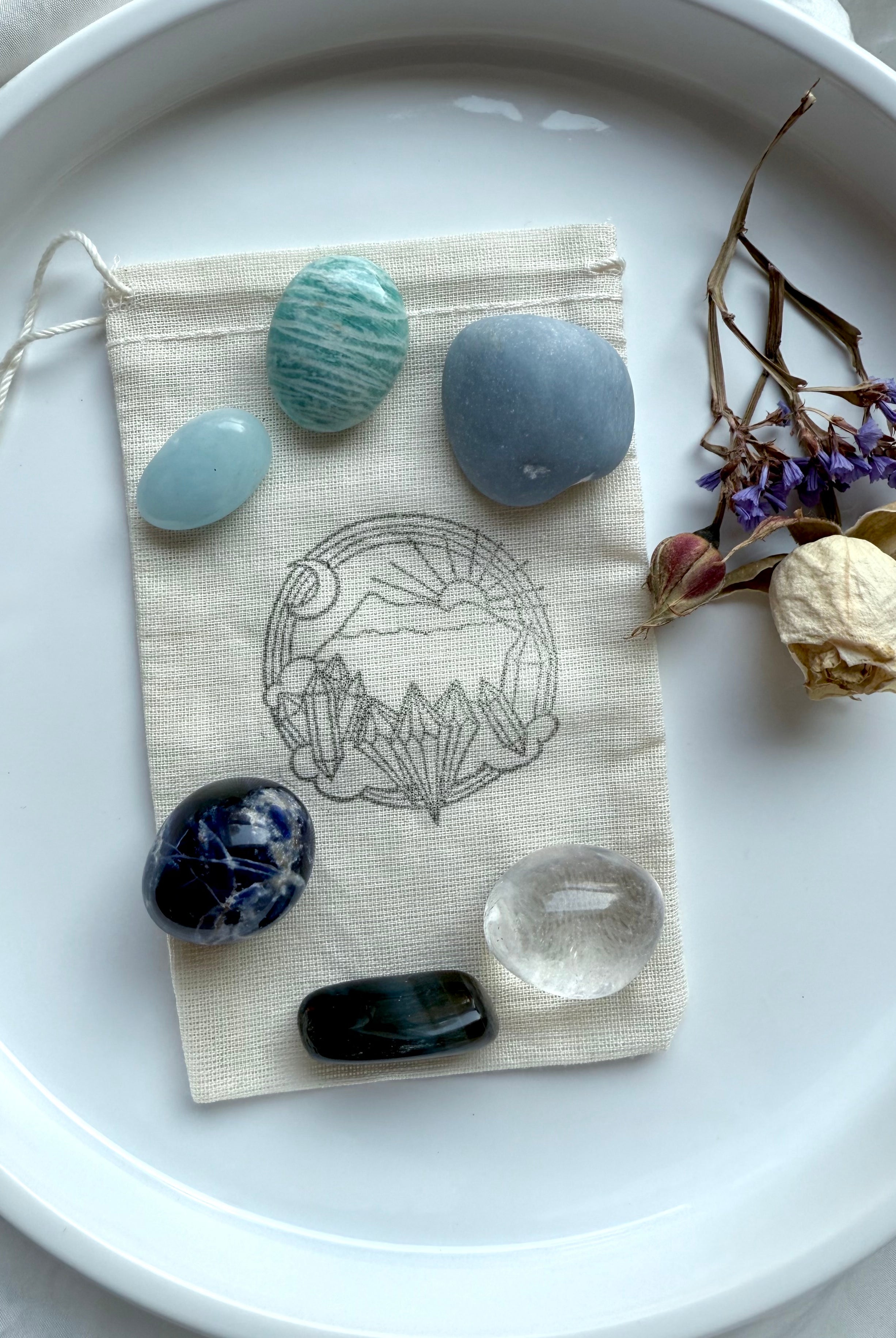 Throat Chakra Crystal Set displayed with cotton pouch and dried flowers — six stones for truth and expression