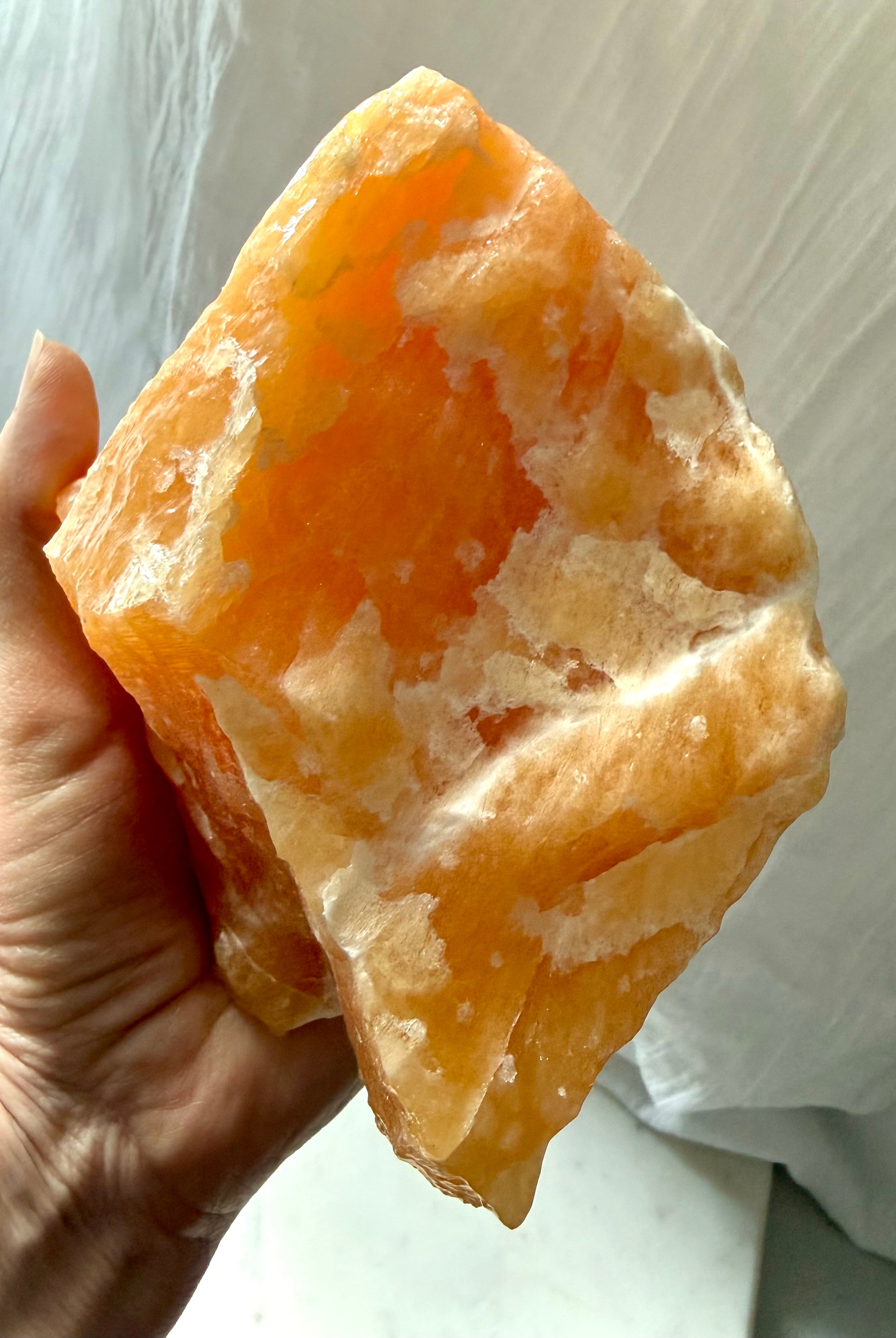 Large self-standing Orange Calcite specimen displaying natural mineral formations and luminous orange translucency