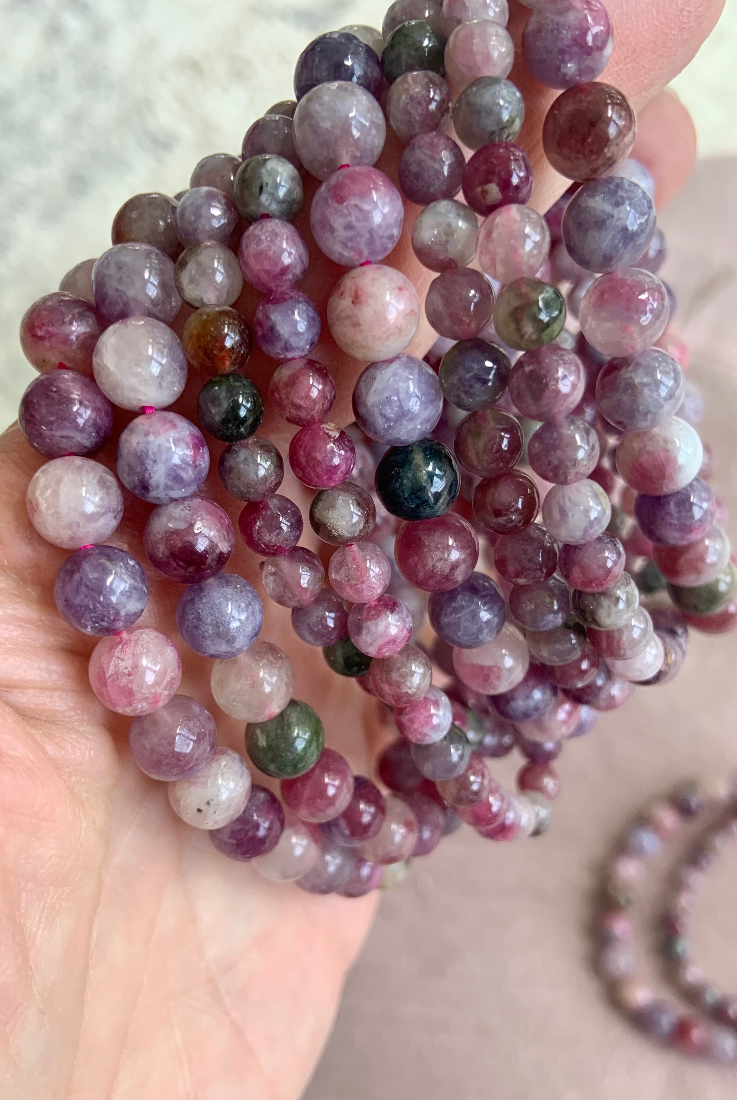 Side view of stacked Green Unicorn Stone bracelets — aka Watermelon Tourmaline in Lepidolite — heart chakra crystal jewelry in mixed bead sizes for anxiety relief + calm