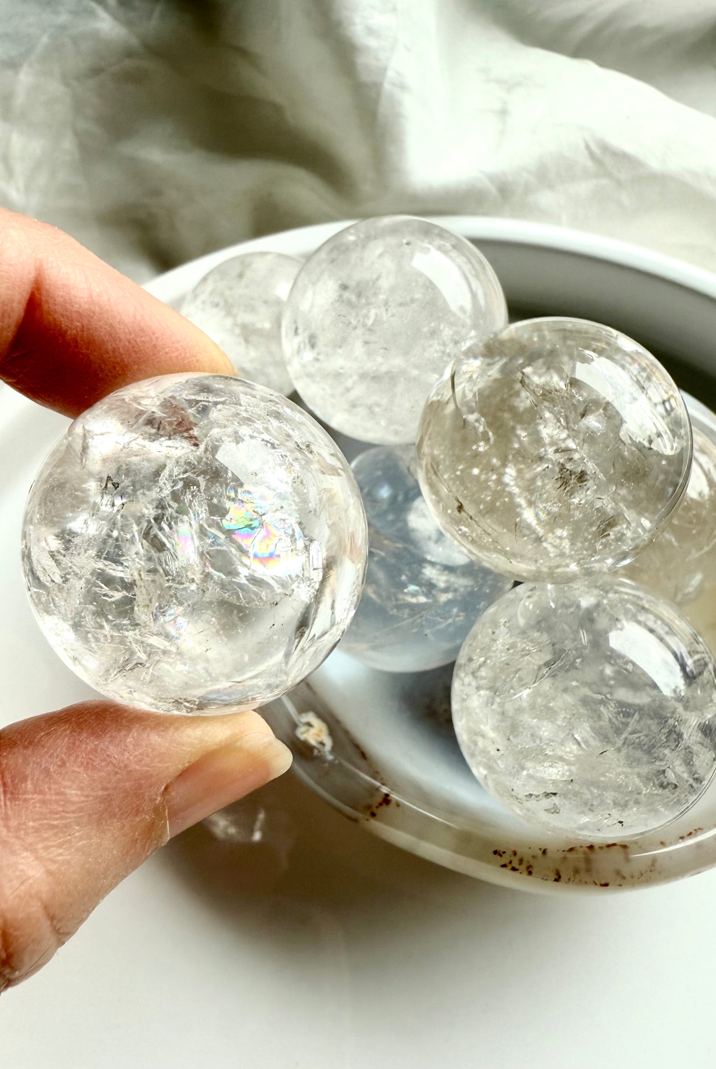 Hand holding a clear Rainbow Quartz sphere with faint rainbow glow – sacred geometry sphere for spiritual clarity and chakra alignment