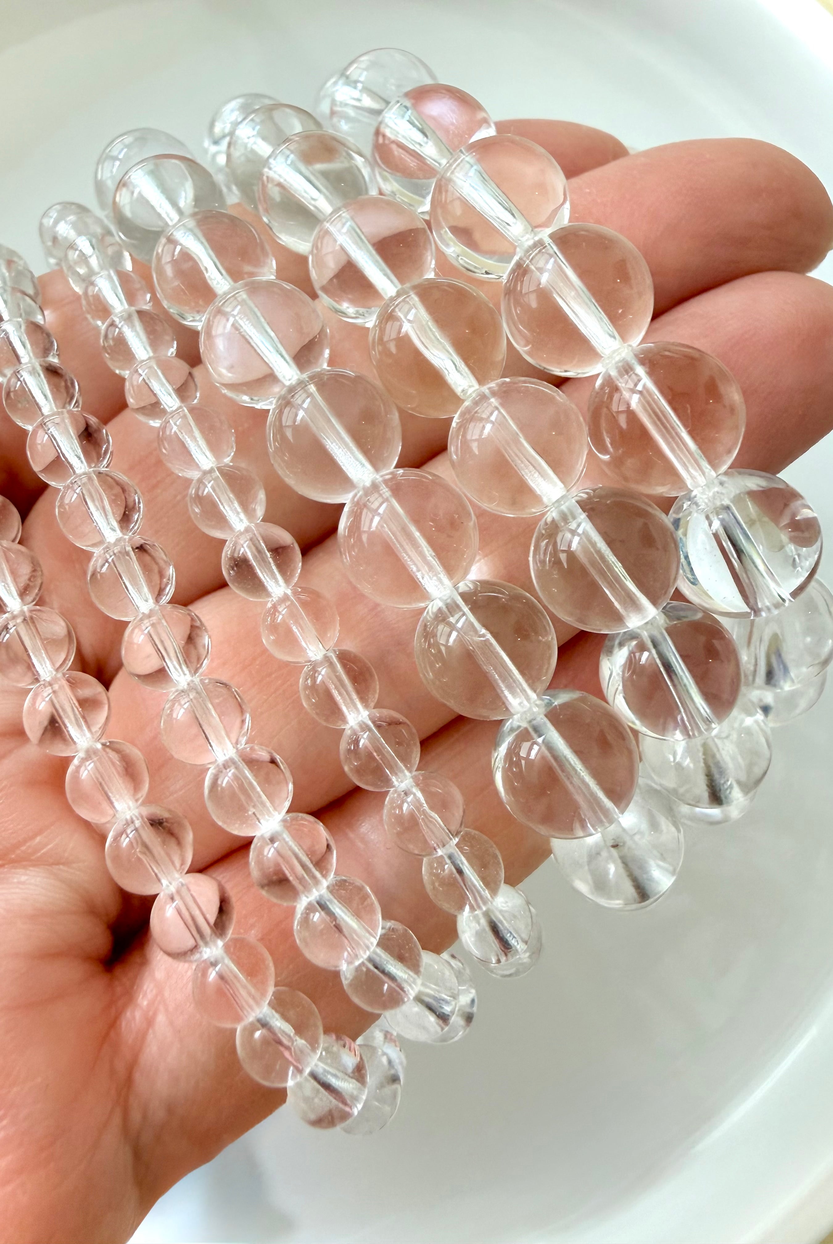 High clarity Clear Quartz bracelets displayed in hand showing transparent polished crystal beads