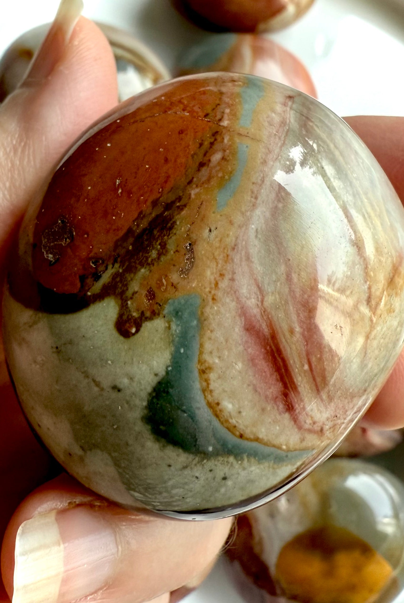 Closeup of a Polychrome Jasper palm stone with earthy tones, unique swirls & grounding crystal energy