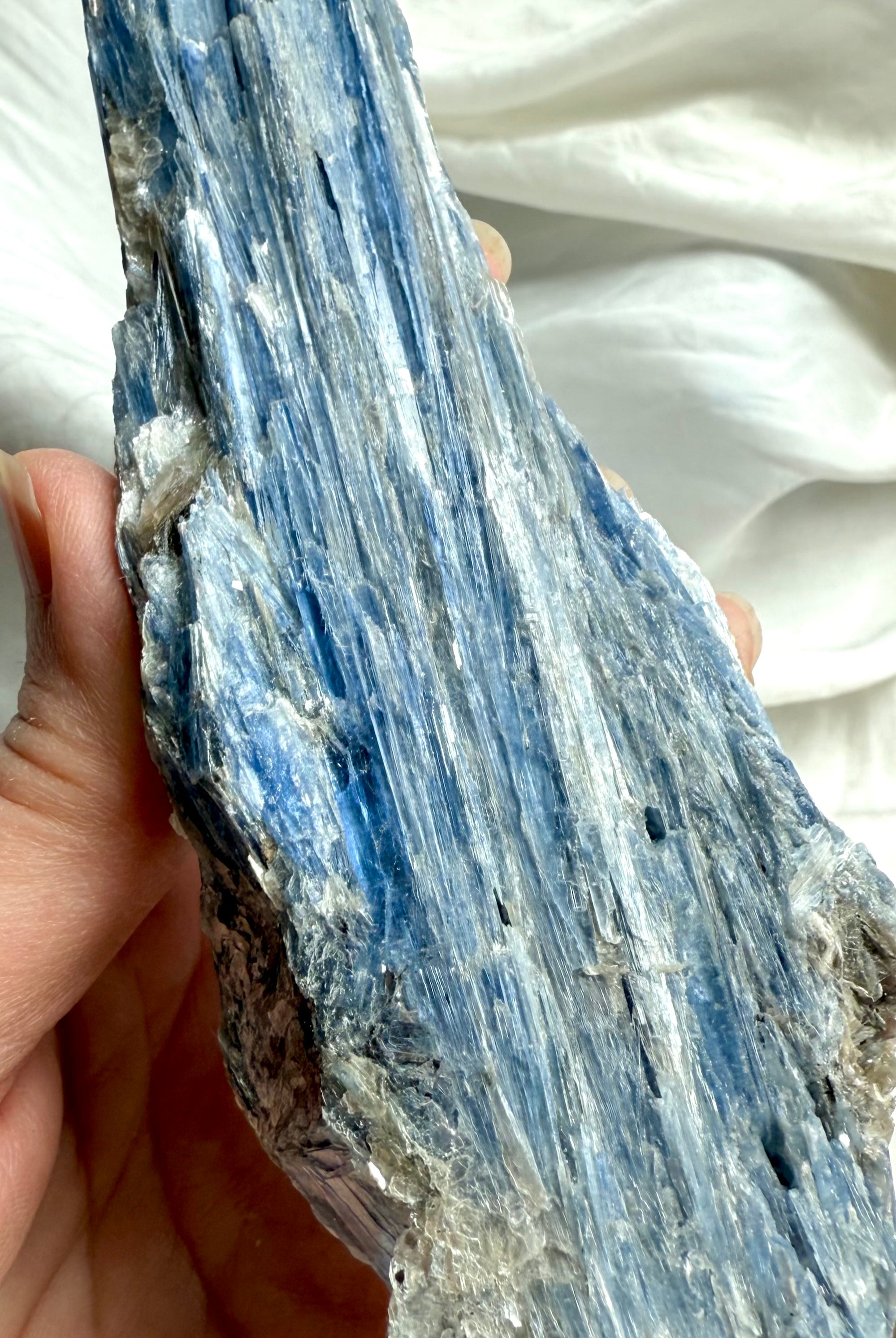 Close up of raw blue kyanite with muscovite mica showing natural flaky crystal texture and silvery shimmer