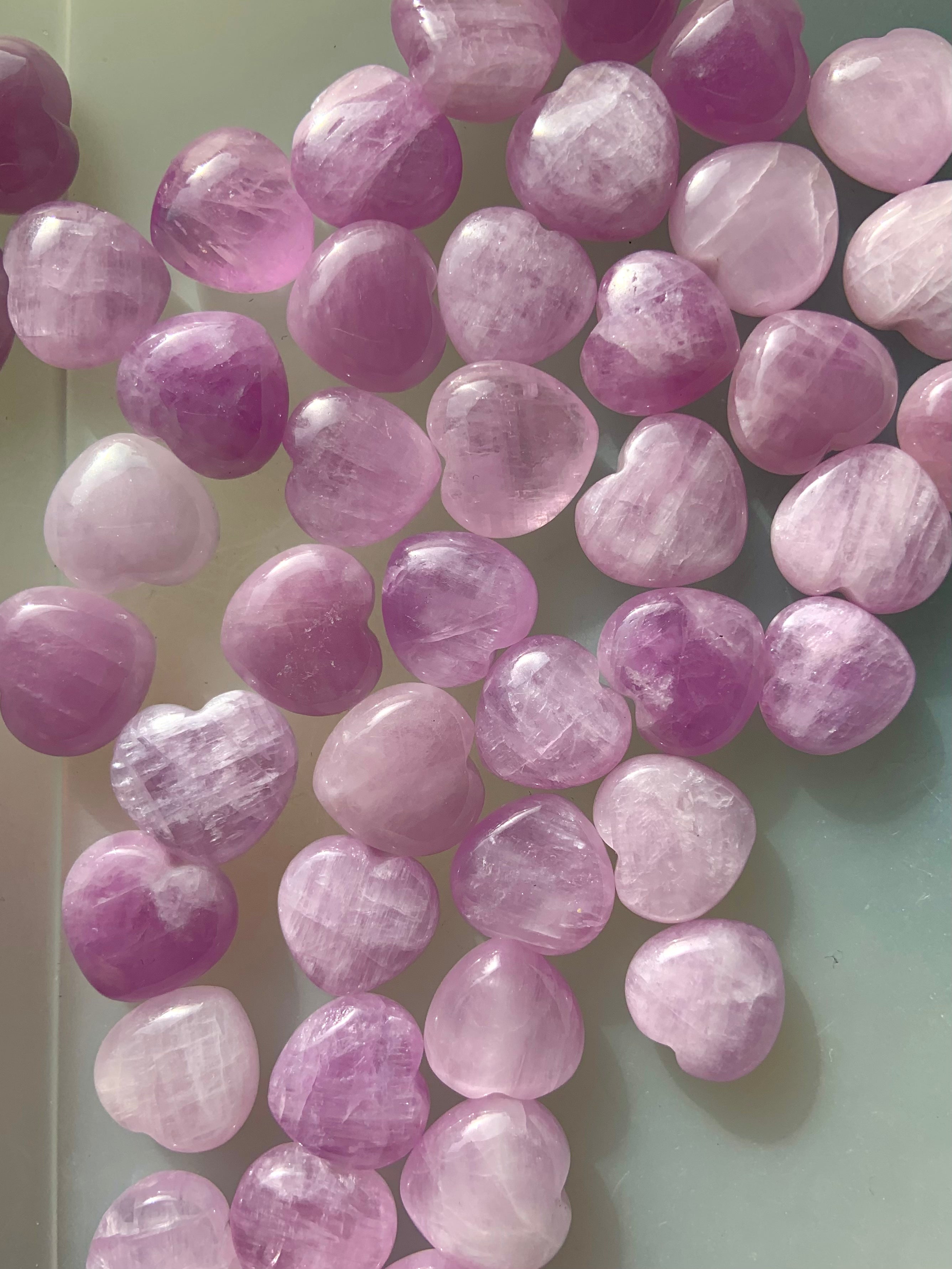 Array of pink Kunzite mini hearts displayed closely together β gentle crystal hearts for love, emotional healing & heart chakra support.