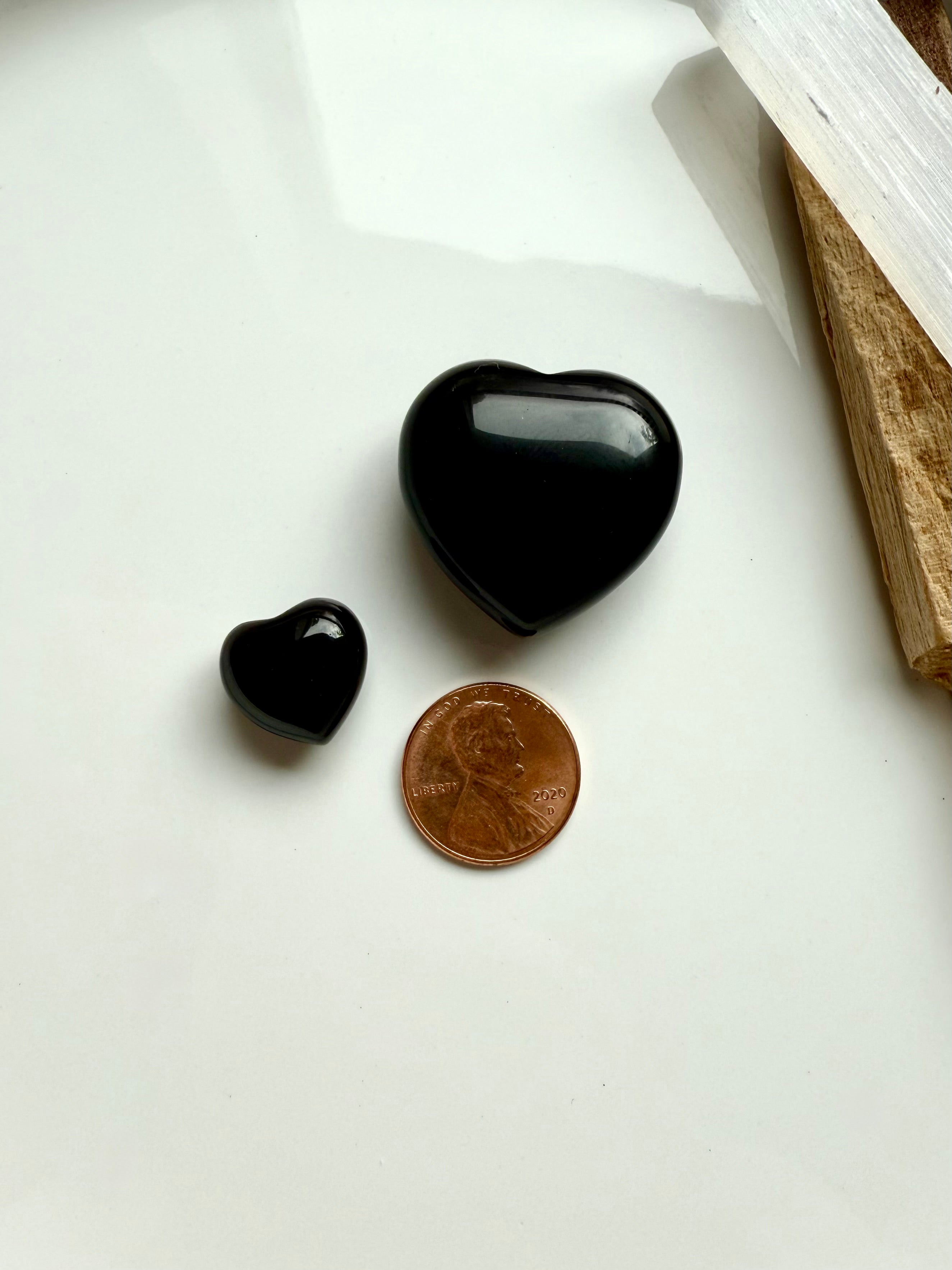 Size comparison of Black Obsidian heart crystals next to a penny and a smaller obsidian heart.