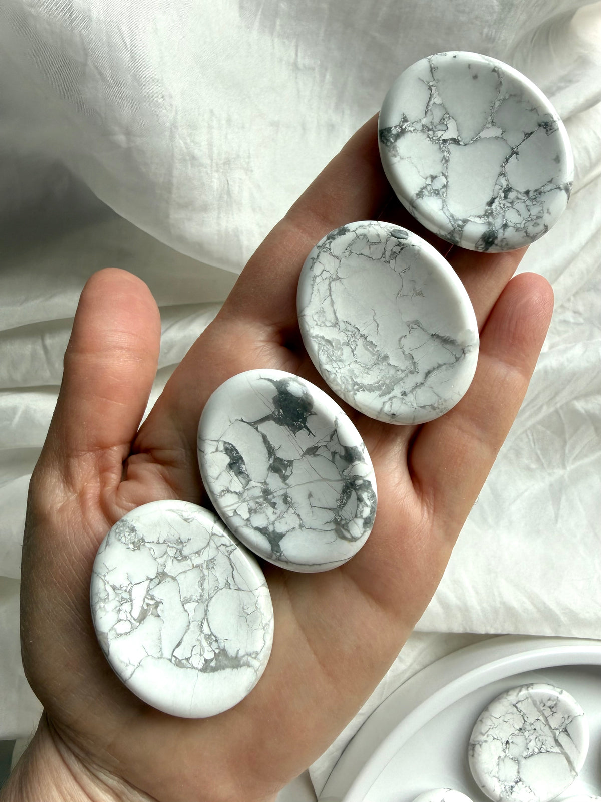 Polished Howlite worry stones held in hand showing smooth oval shape, gray veining and natural pattern variation