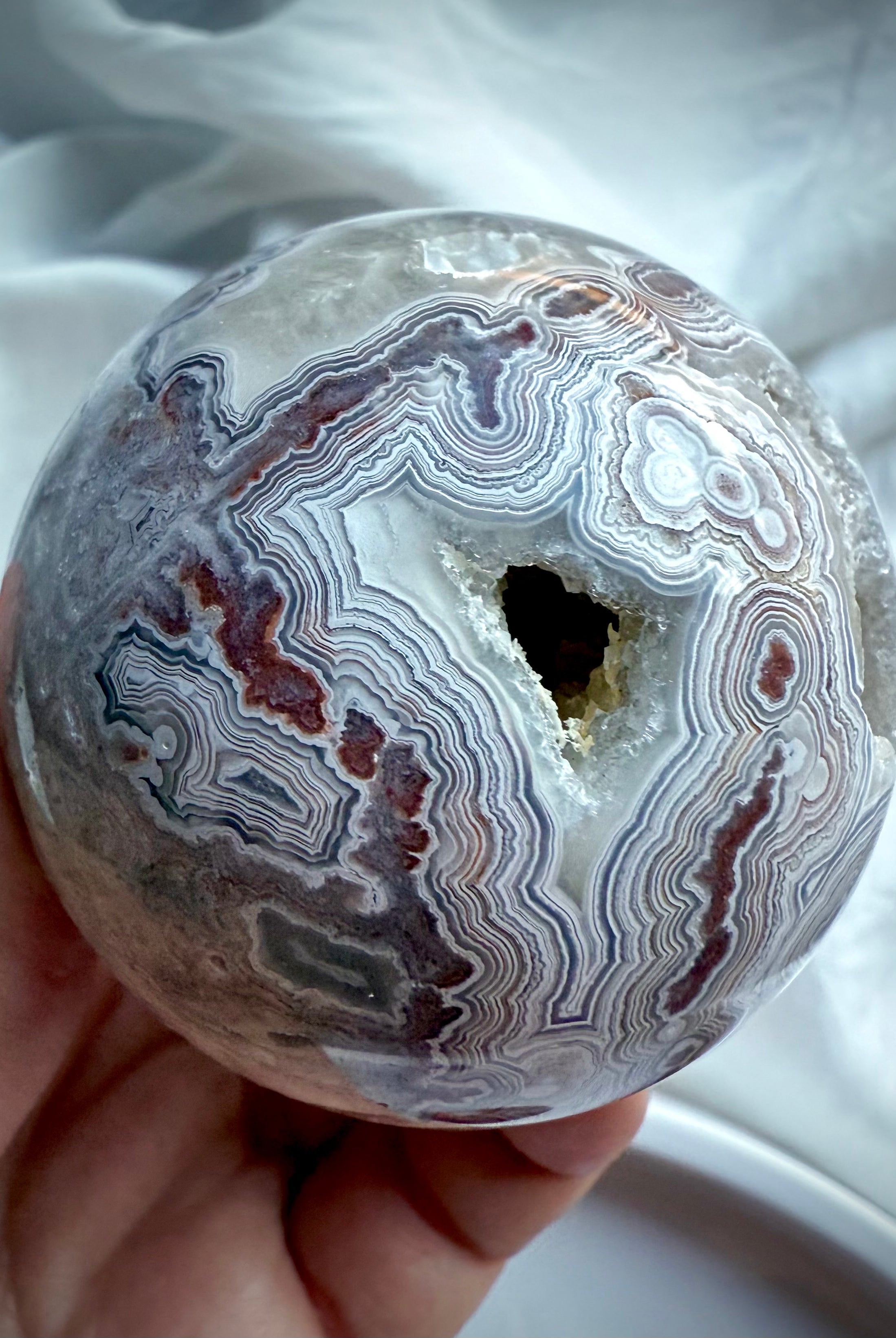 Crazy Lace Agate sphere with sparkling druzy pocket and bold concentric banding in shades of white, grey, and burgundy