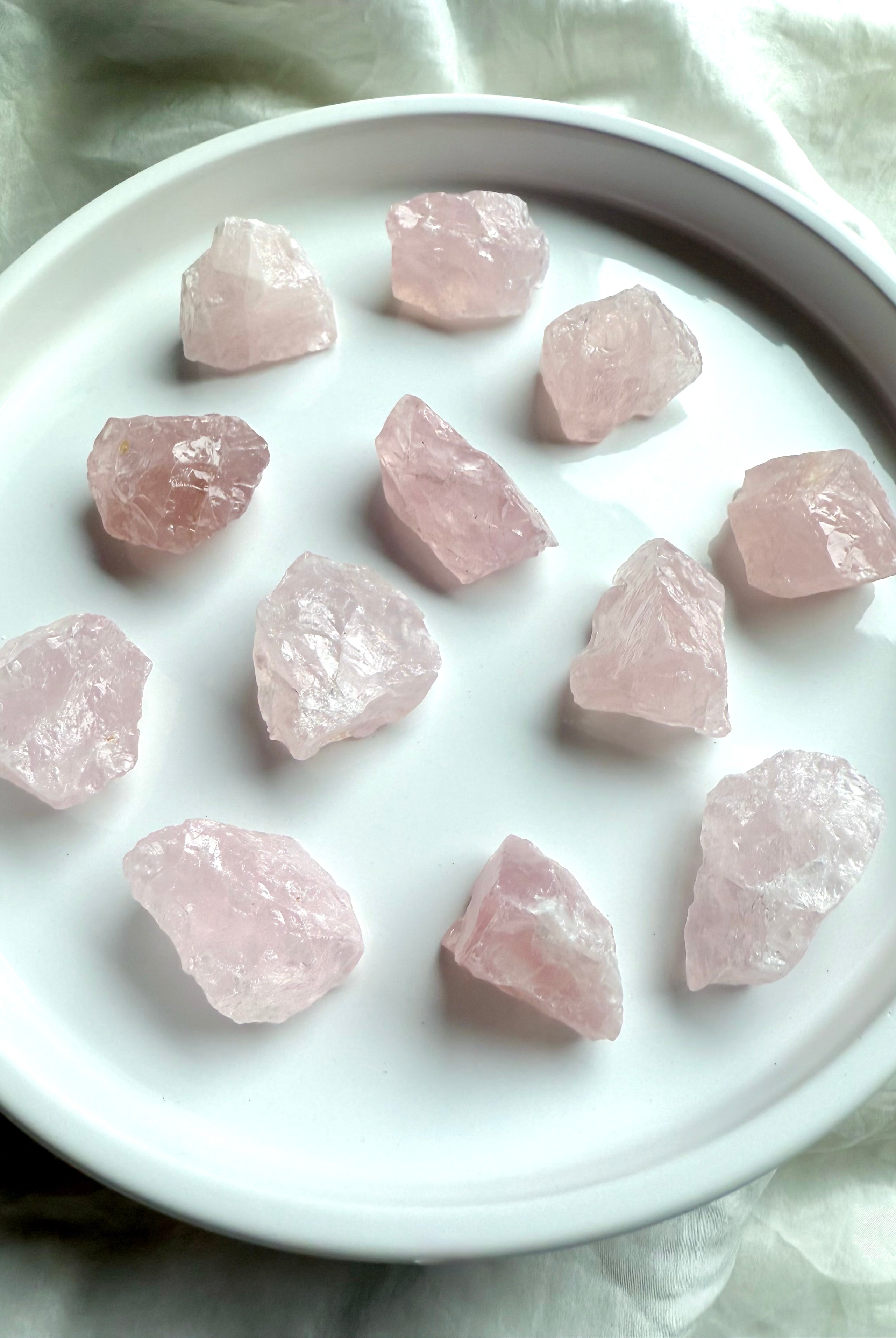 Small raw Rose Quartz chunks with translucent pink color on white. Natural crystals for peace & love.