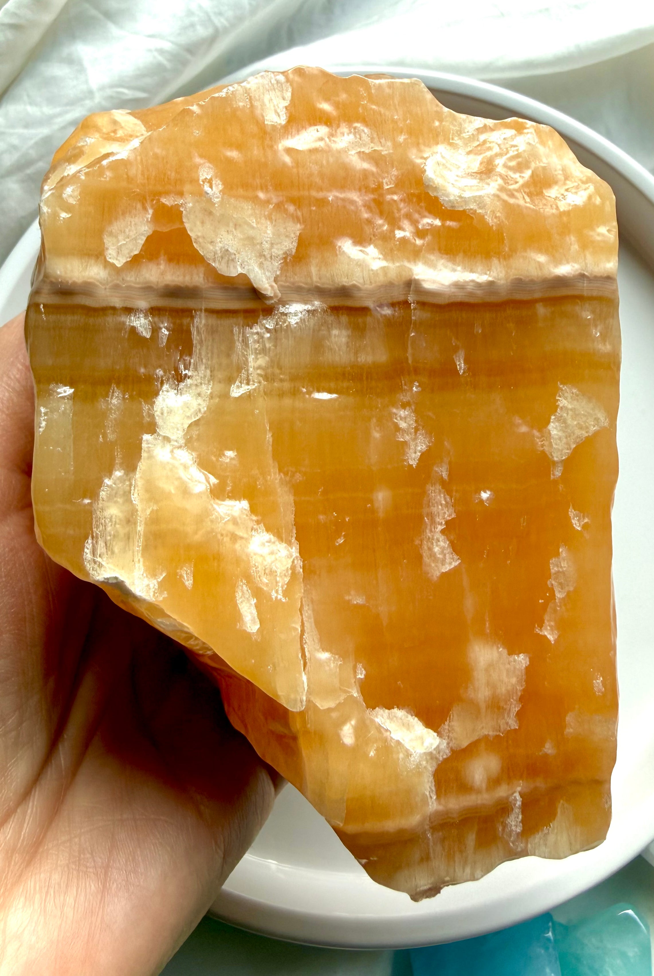 Handheld Orange Calcite crystal chunk with raw yet refined finish and glowing translucent orange calcite