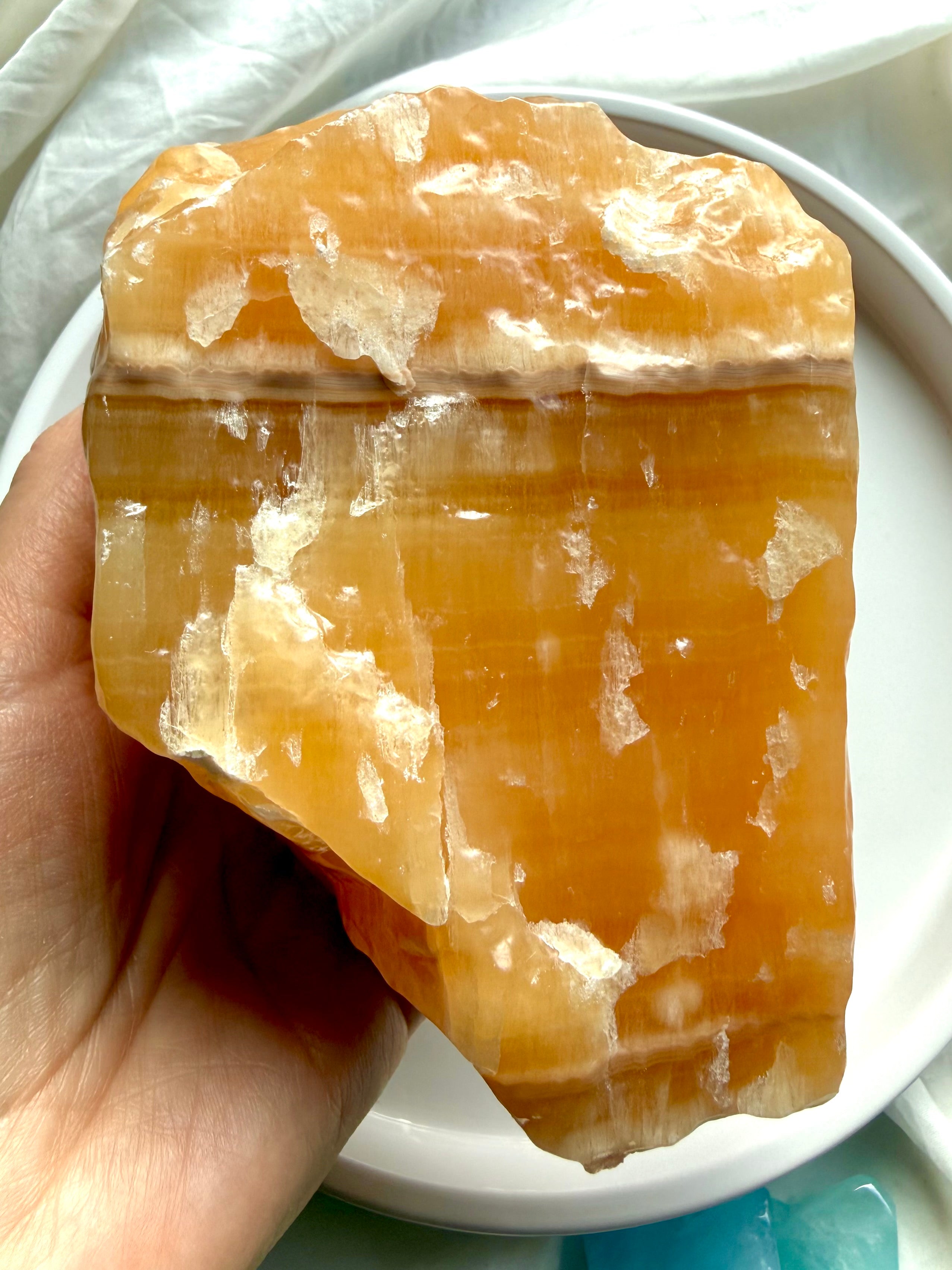 Handheld Orange Calcite crystal chunk with raw yet refined finish and glowing translucent orange calcite