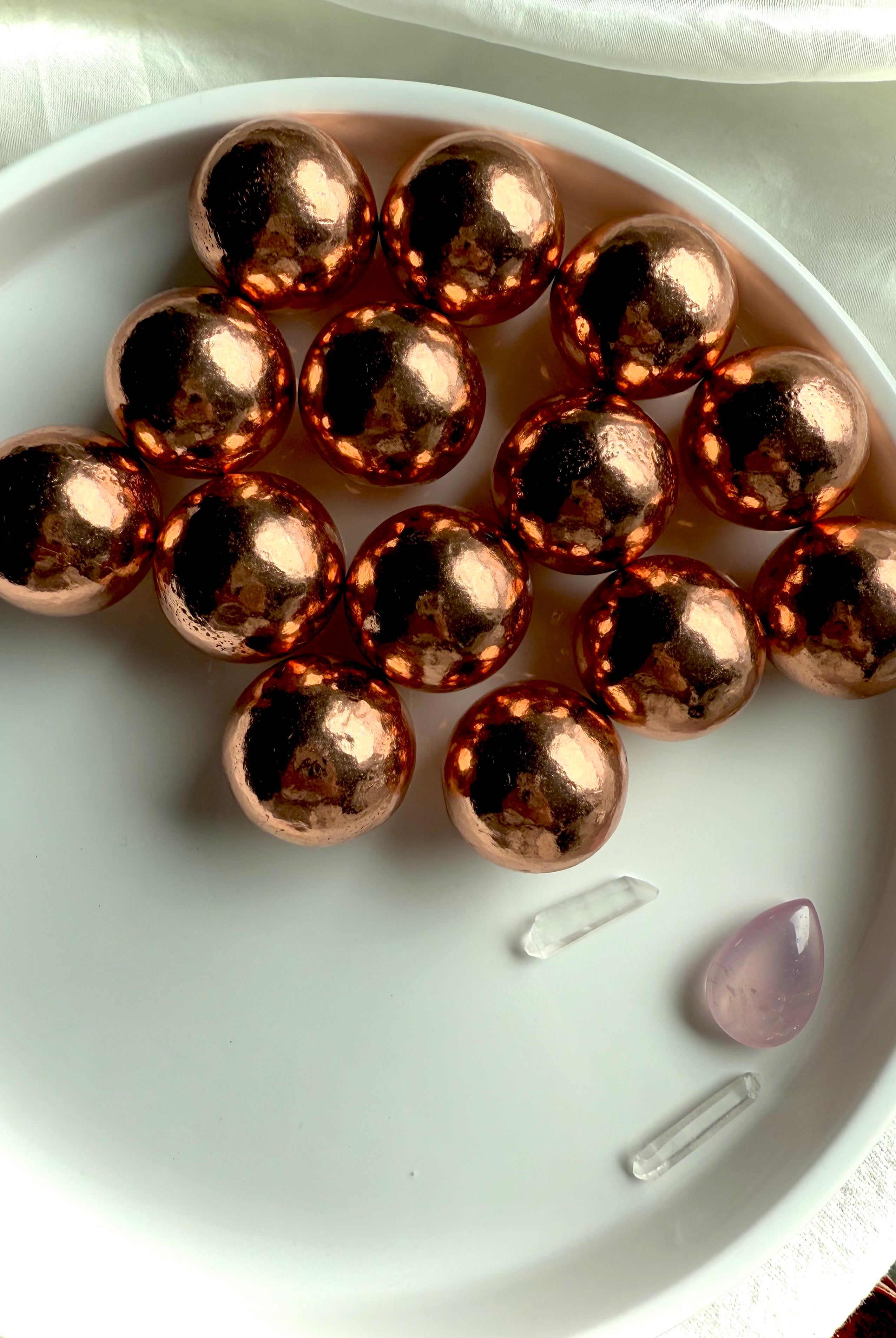 a white plate filled with small native copper spheres showing the glowing natural copper color