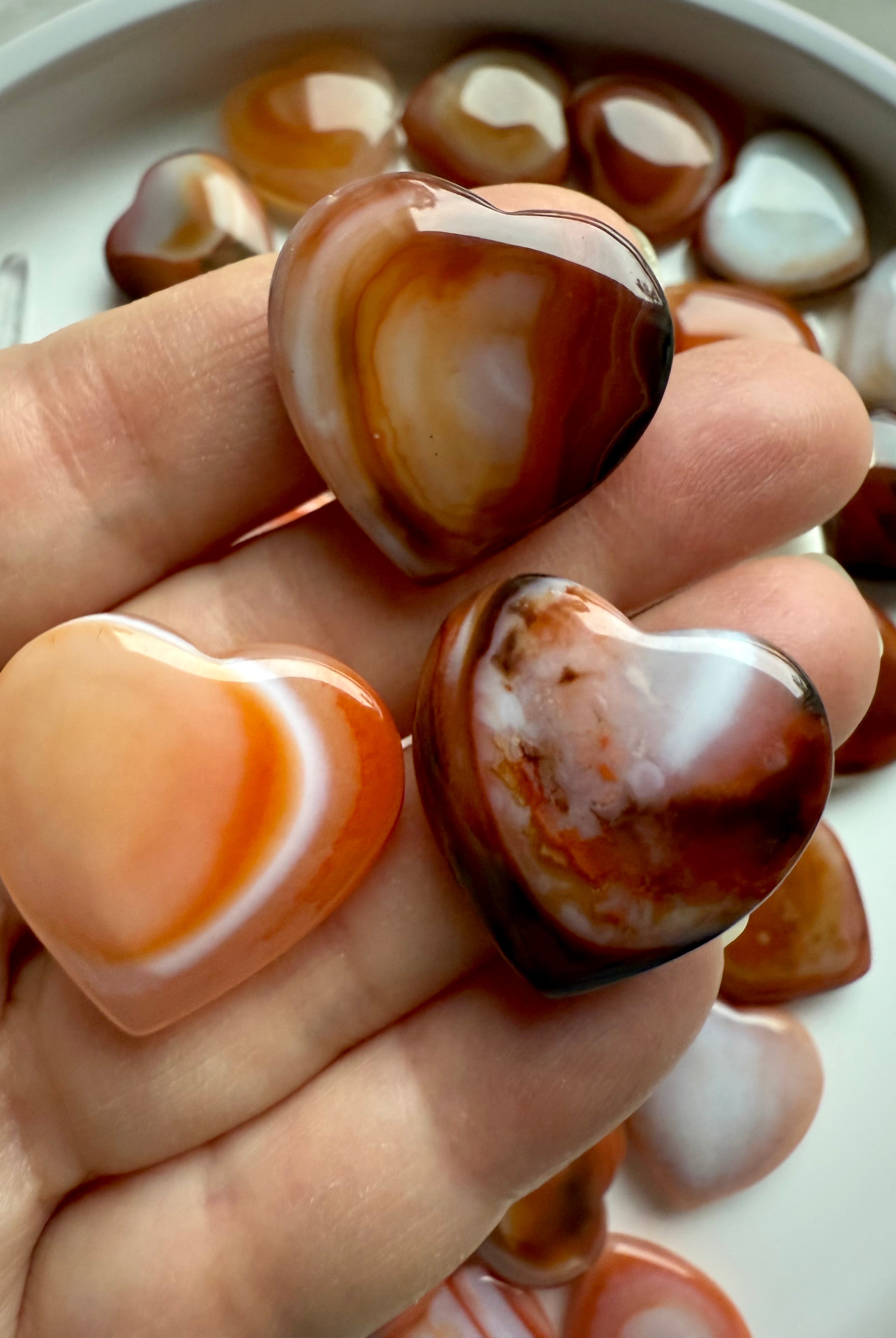 Mini Carnelian heart held in hand, small polished sacral chakra crystal for creativity, passion, and joyful energy