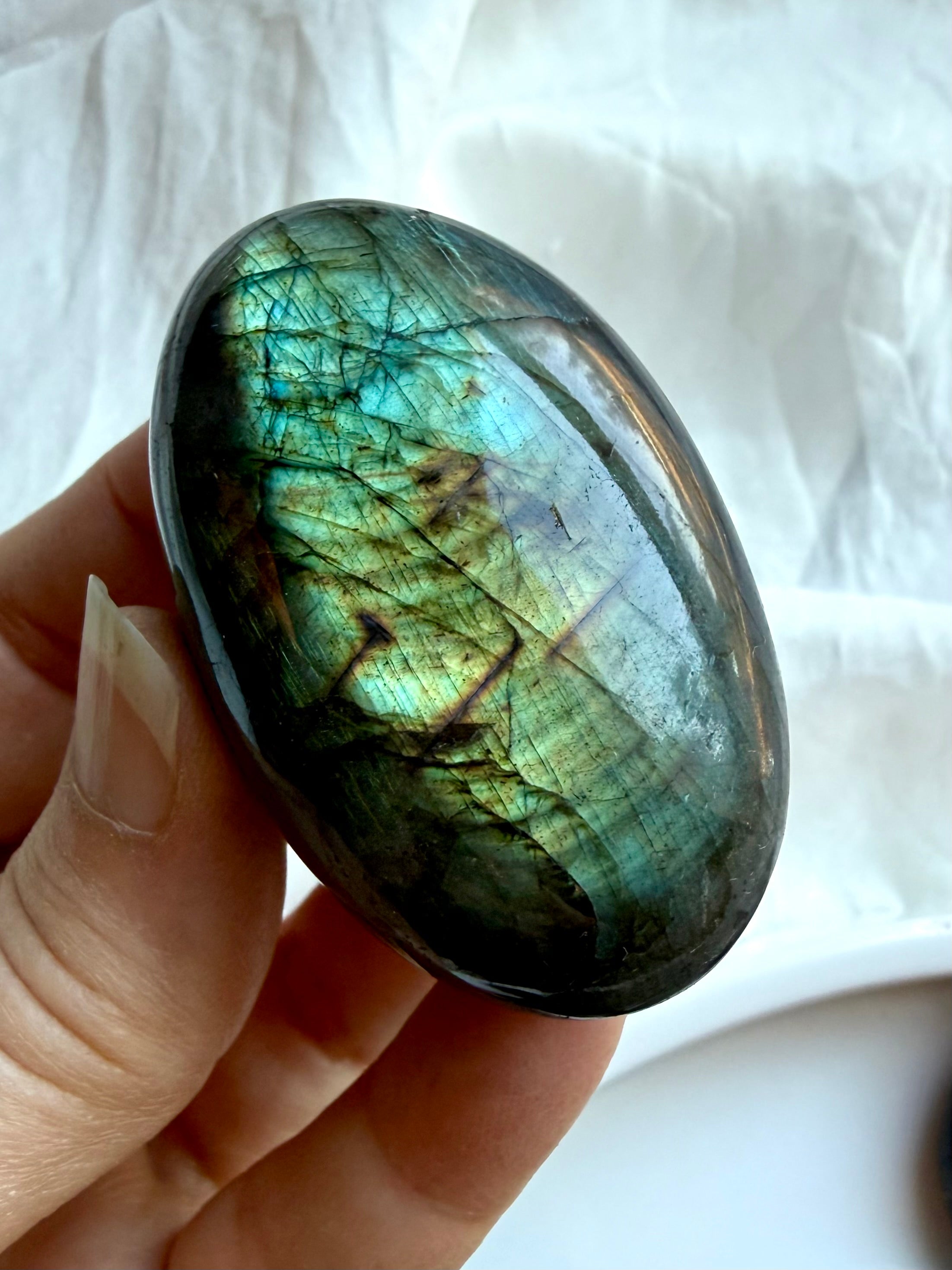 Green flash Labradorite palm stone held in hand with vibrant labradorescence and natural mineral patterns