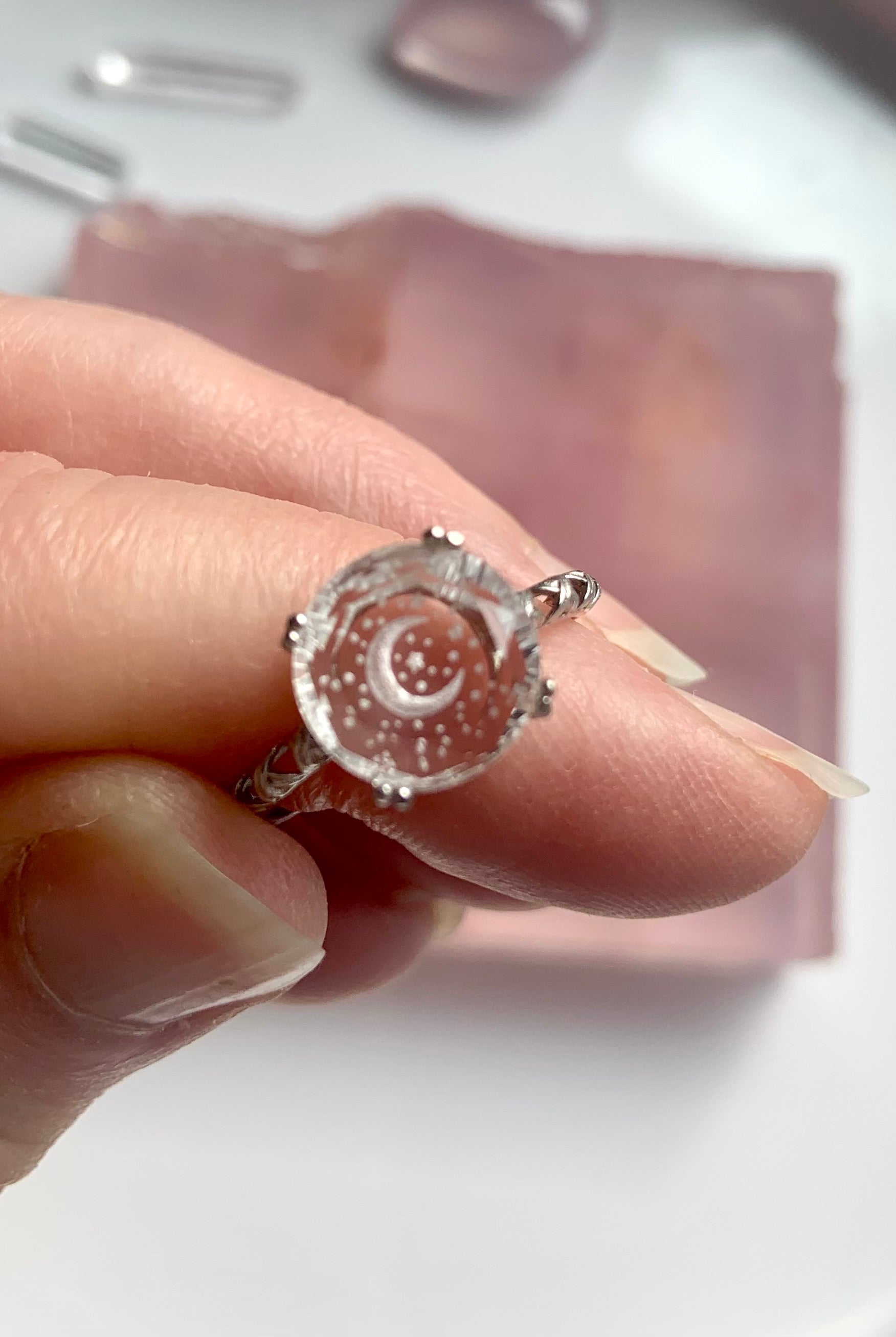 close-up of celestial etched clear quartz ring held between fingers