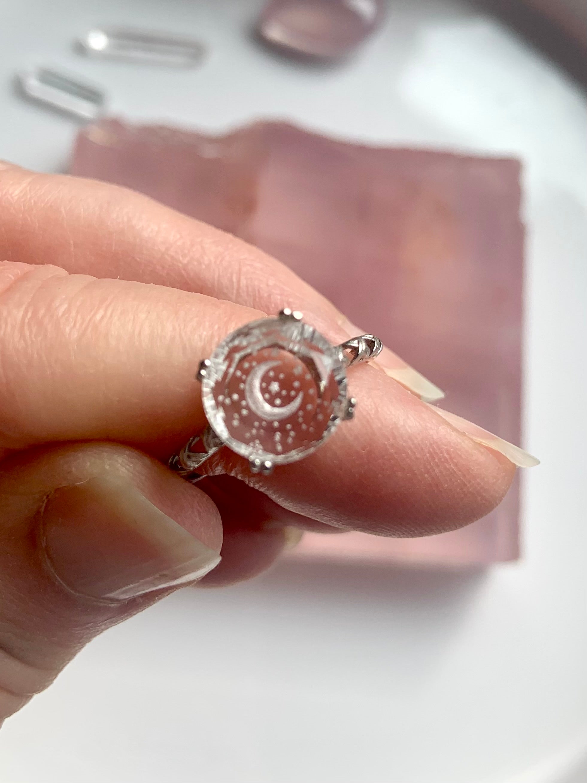 close-up of celestial etched clear quartz ring held between fingers