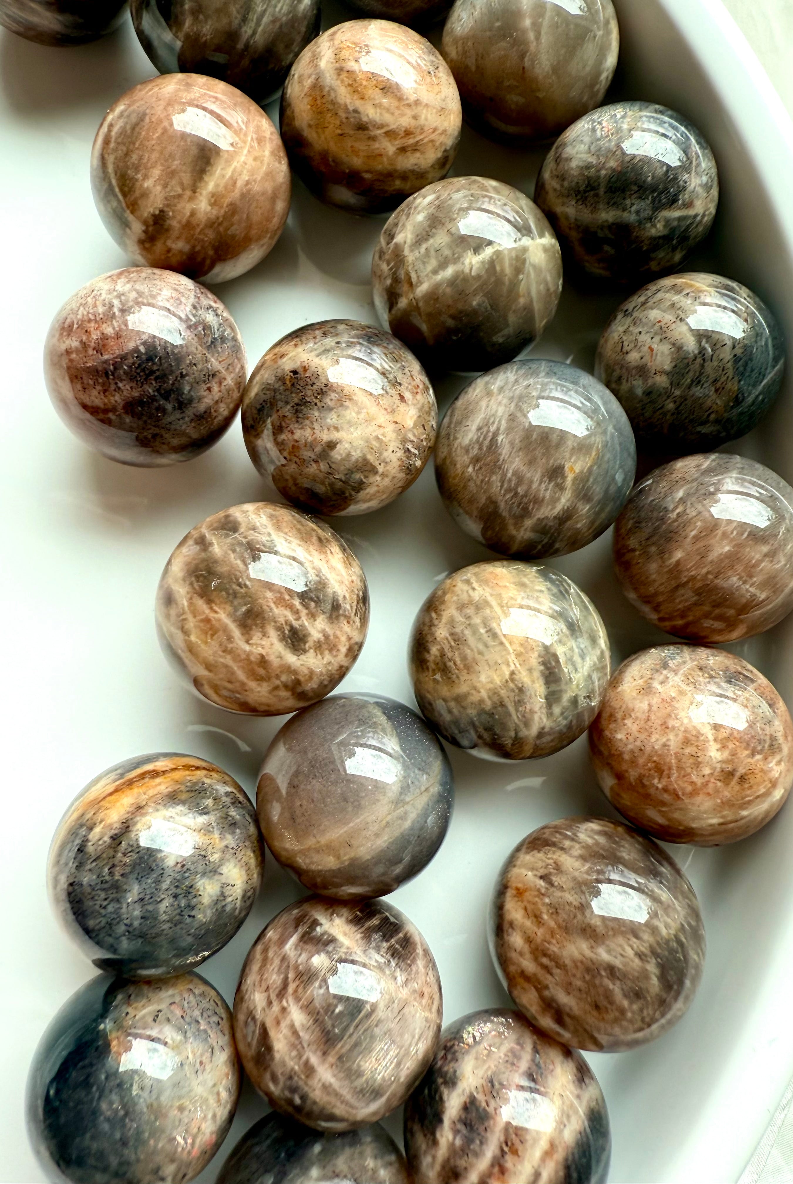 Mini Black Moonstone spheres with Sunstone shimmer arranged on white background